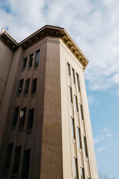 低视角下的现代城市建筑，映衬着部分多云的天空