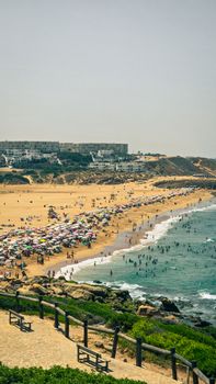 Discover the vibrant summer scene at a bustling beach in Casablanca, Morocco, filled with colorful umbrellas and joyful beachgoers.