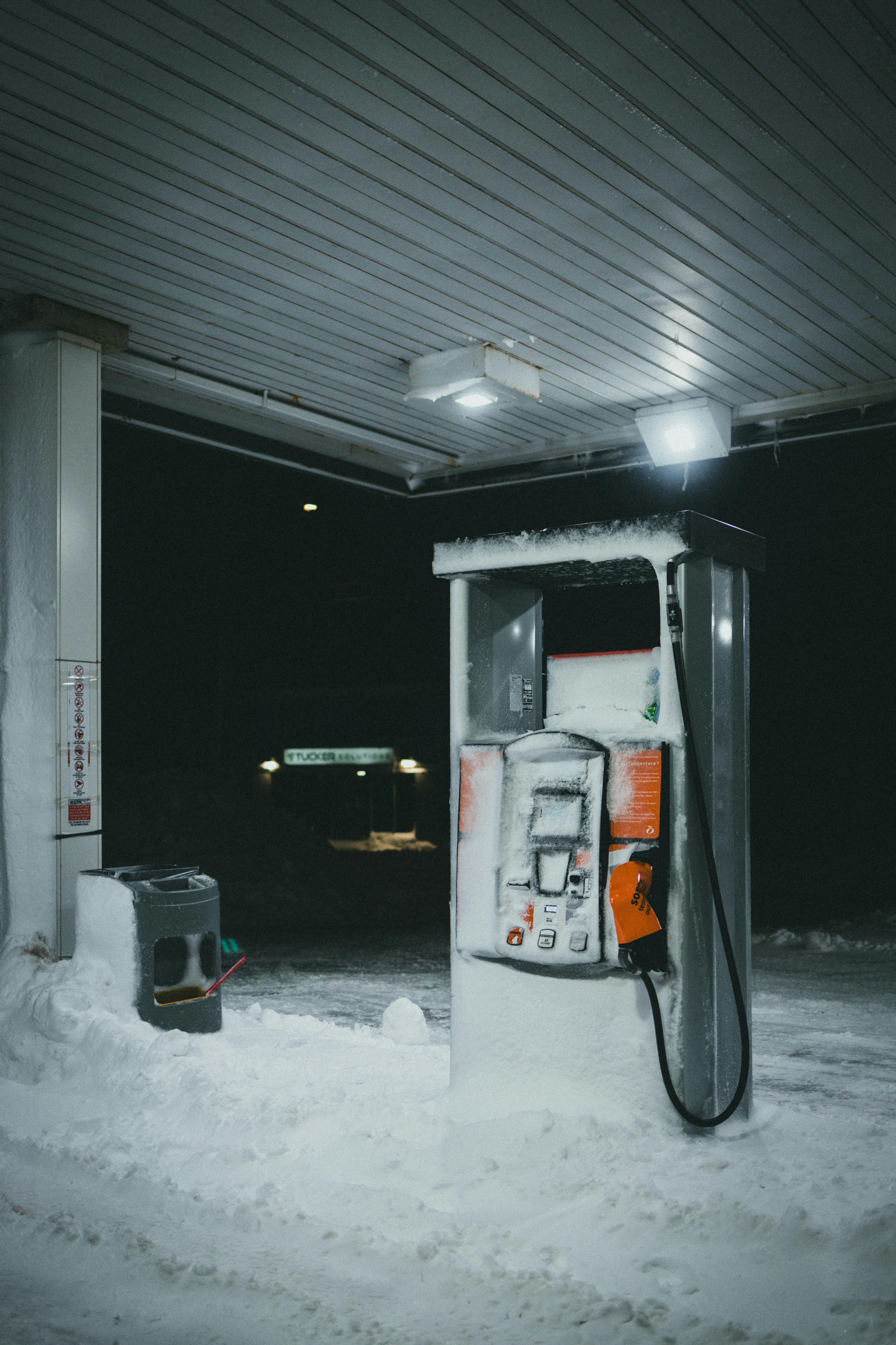 Gratis Una pompa di benzina solitaria coperta di neve in una stazione di servizio in una notte invernale. Foto a disposizione