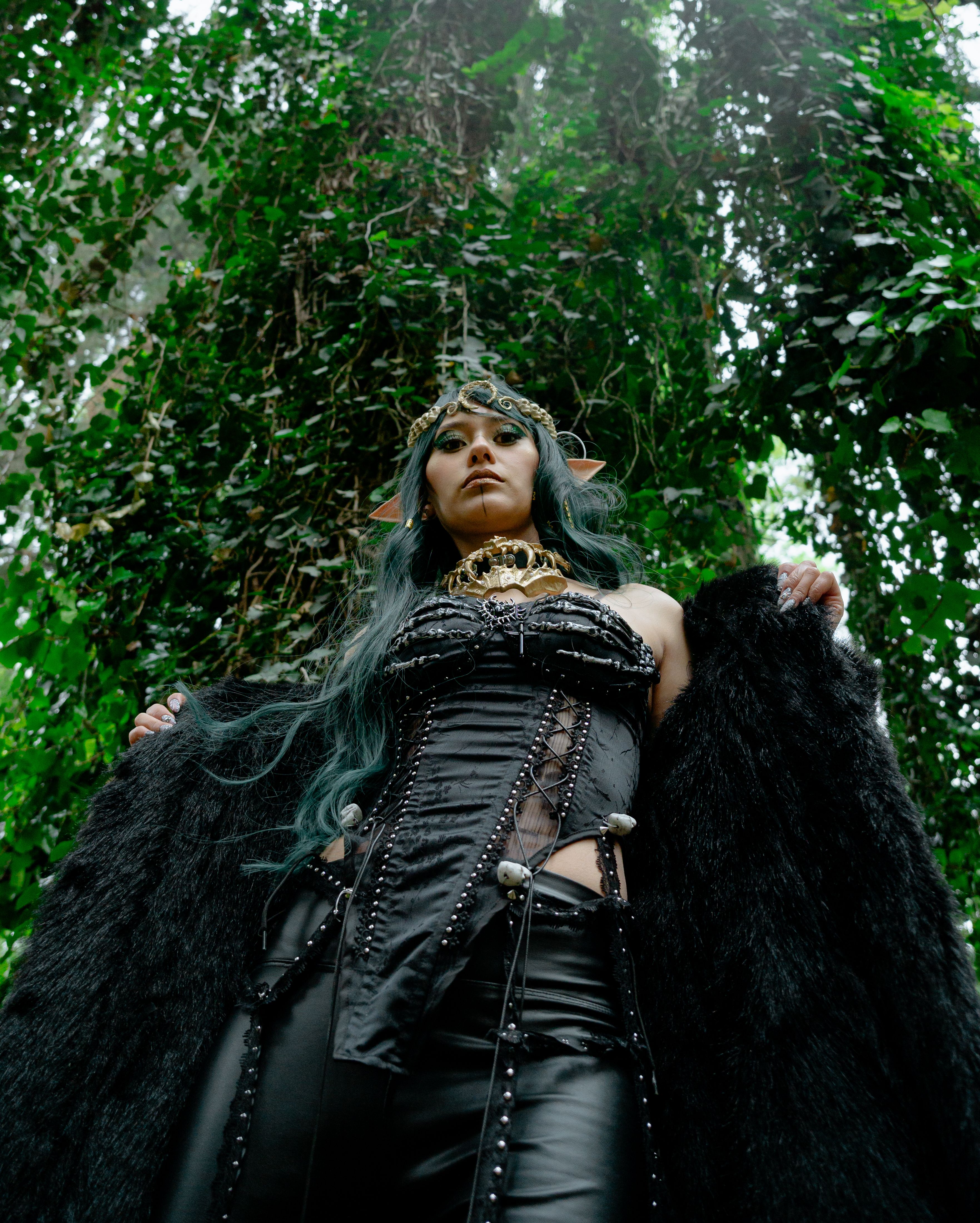 A striking fantasy cosplay portrait of a woman in an enchanted forest setting.