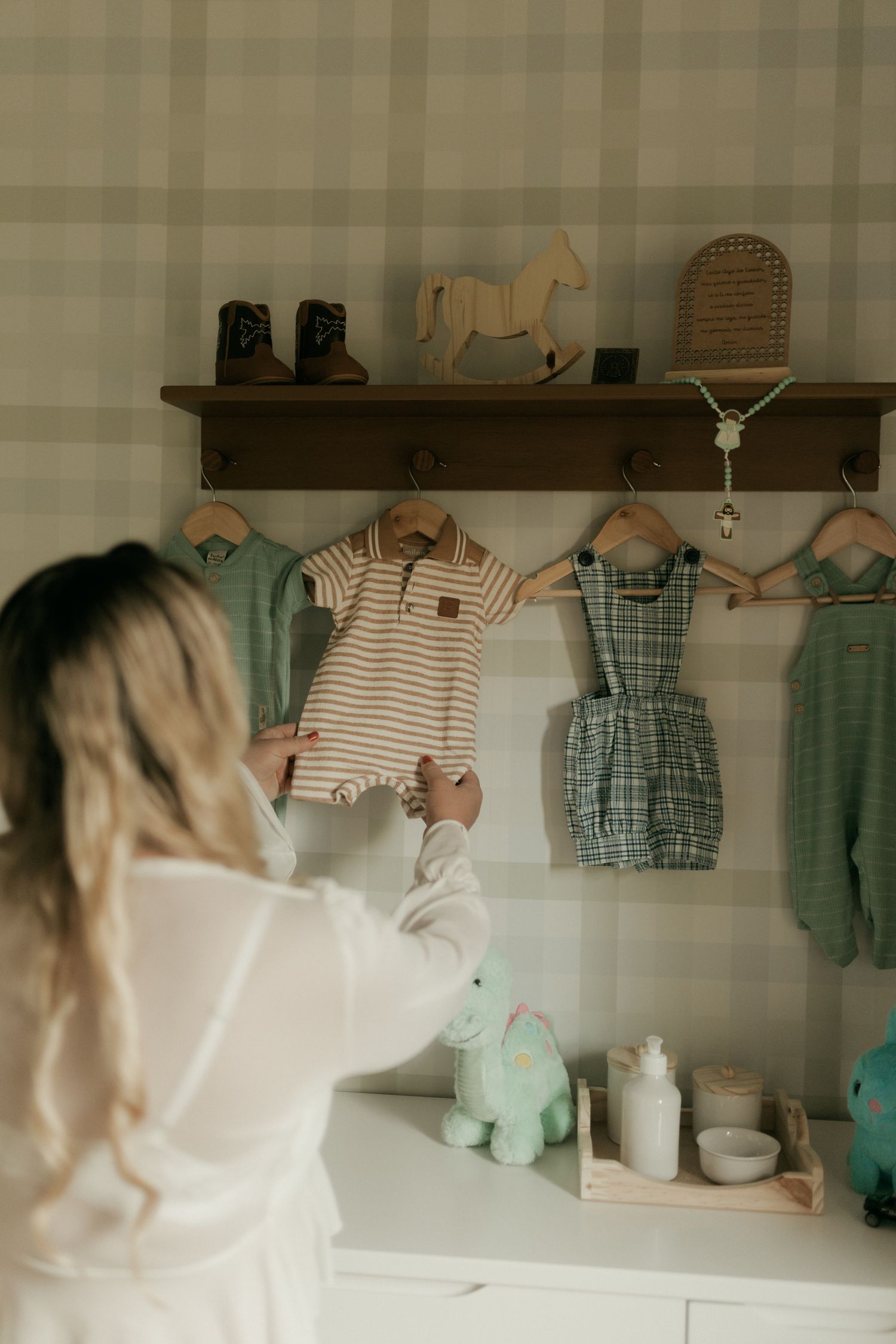 Maman sélectionnant soigneusement des vêtements de bébé dans une chambre lumineuse