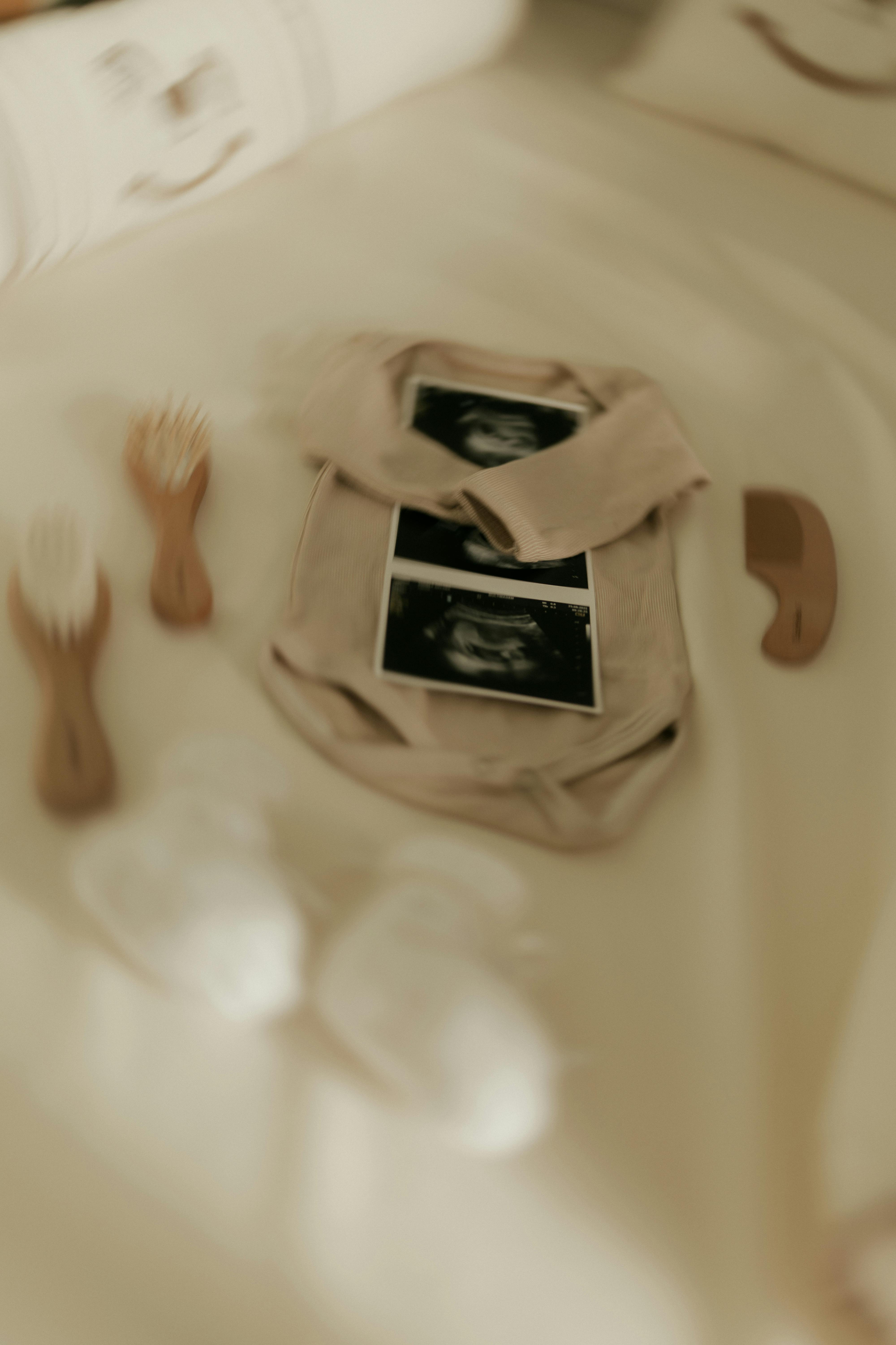 Gratis Babyklær med ultralydbilder på en seng, som symboliserer et nytt familietillegg. Arkivbilde