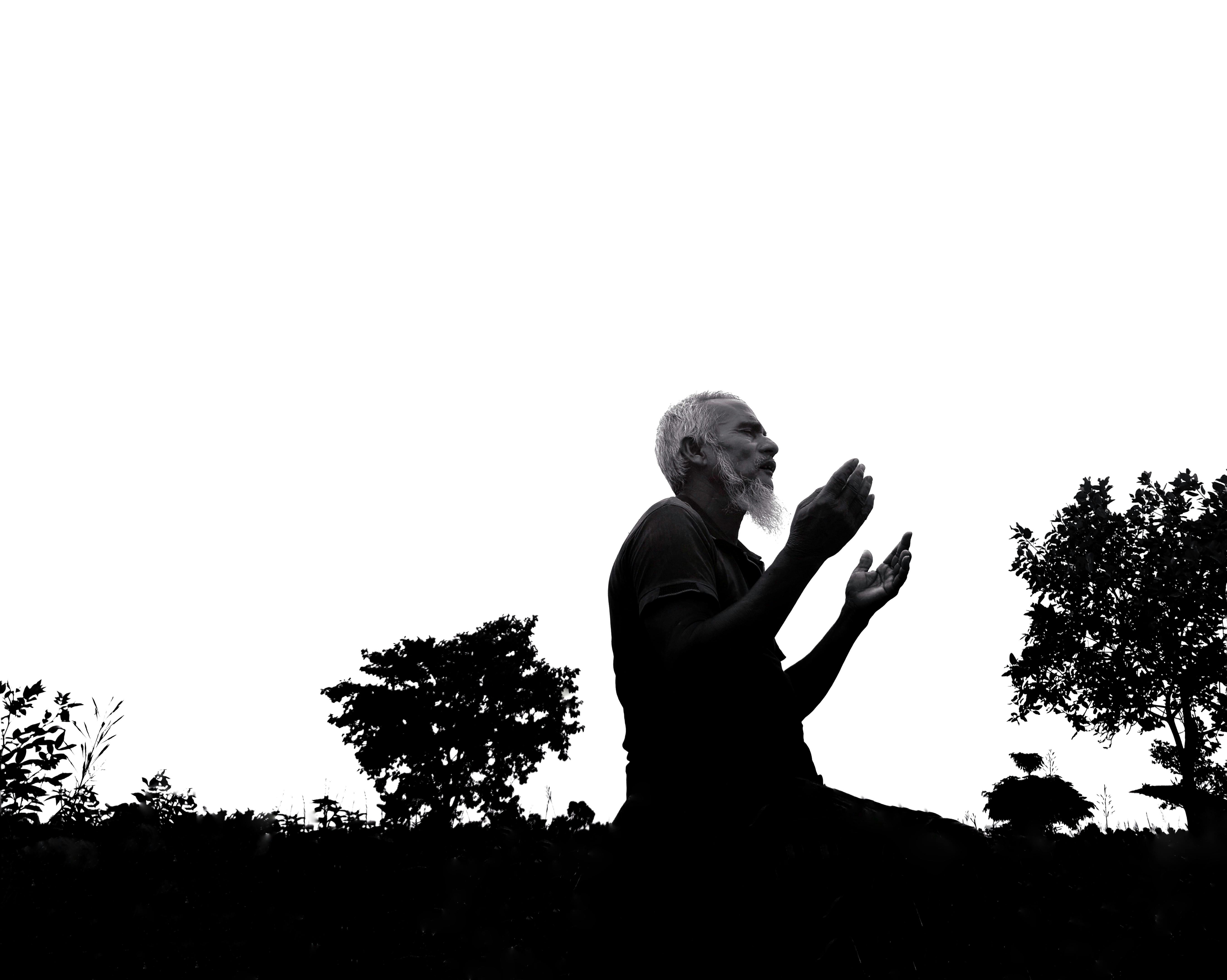 Gratis Silhuett av en eldre mann som ber utendørs, og fremhever åndelig refleksjon. Arkivbilde