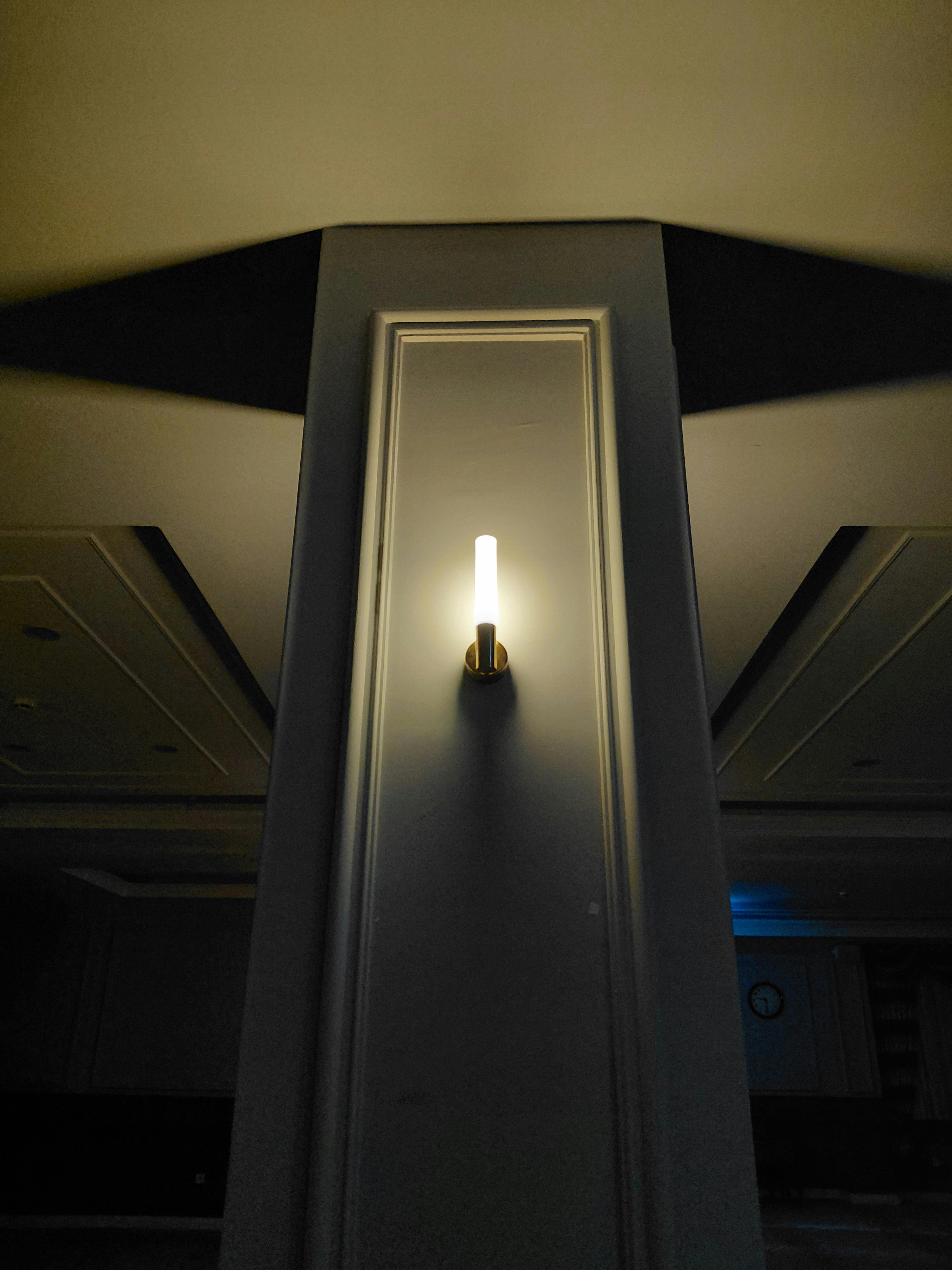 Gratis Elegant vegglampe som lyser opp et dunkelt innvendig rom med skyggekontraster. Arkivbilde