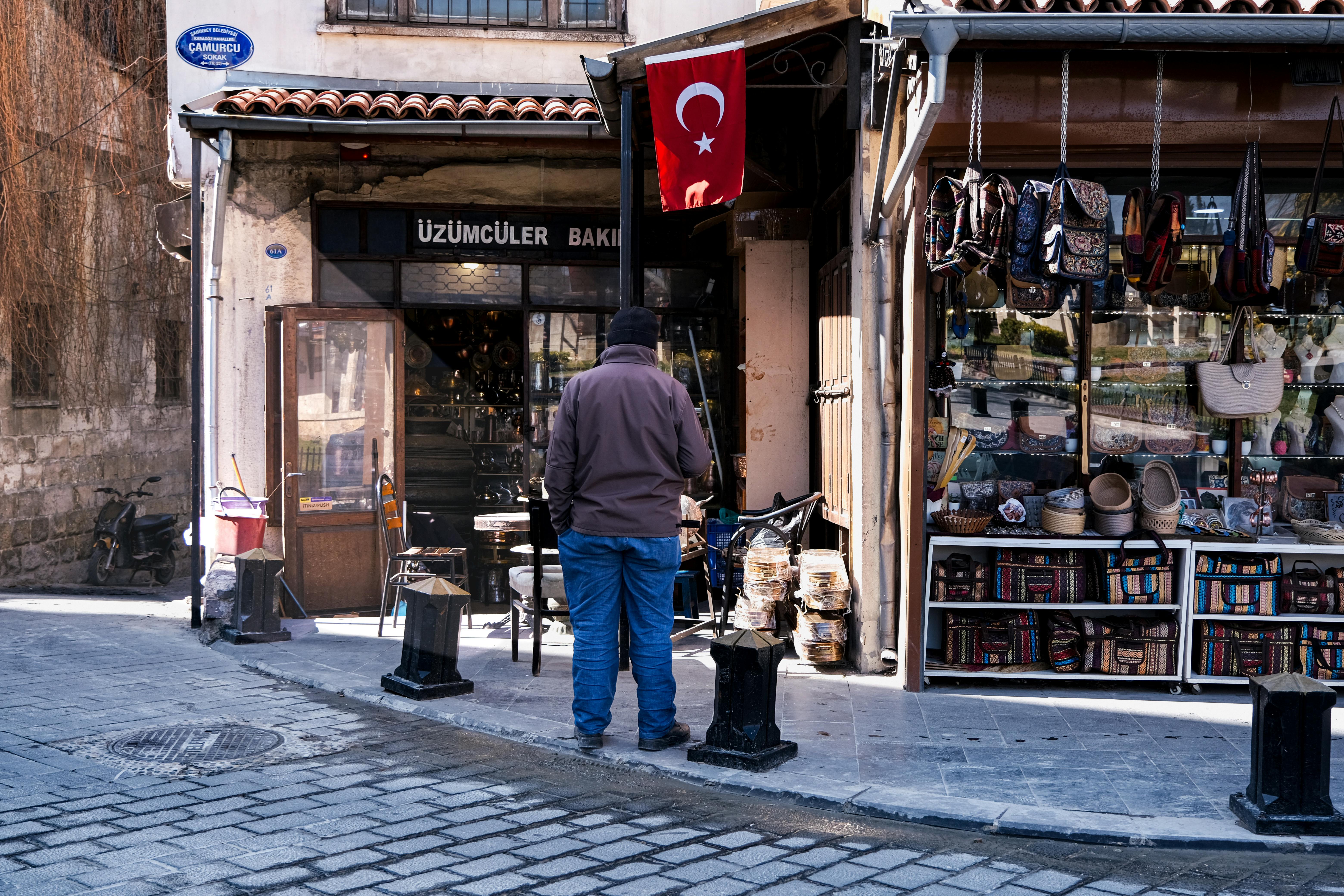Gratis Mann som handler i en tradisjonell tyrkisk markedsgate med butikker og flagg. Arkivbilde