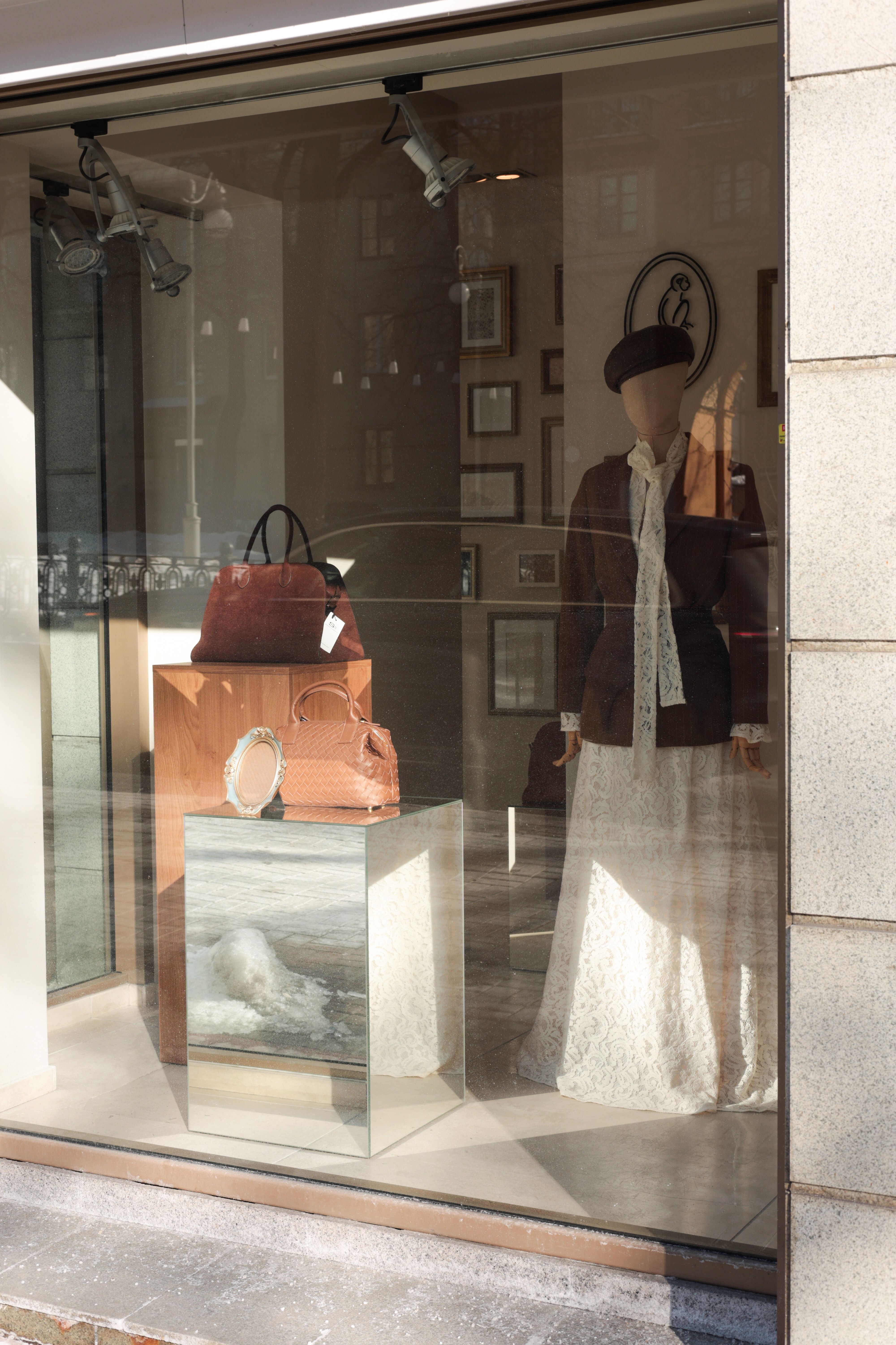 Elegant storefront display featuring a mannequin, leather handbags, and fashion accessories.