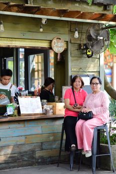Two women sitting at an outdoor cafe counter enjoying a sunny day.