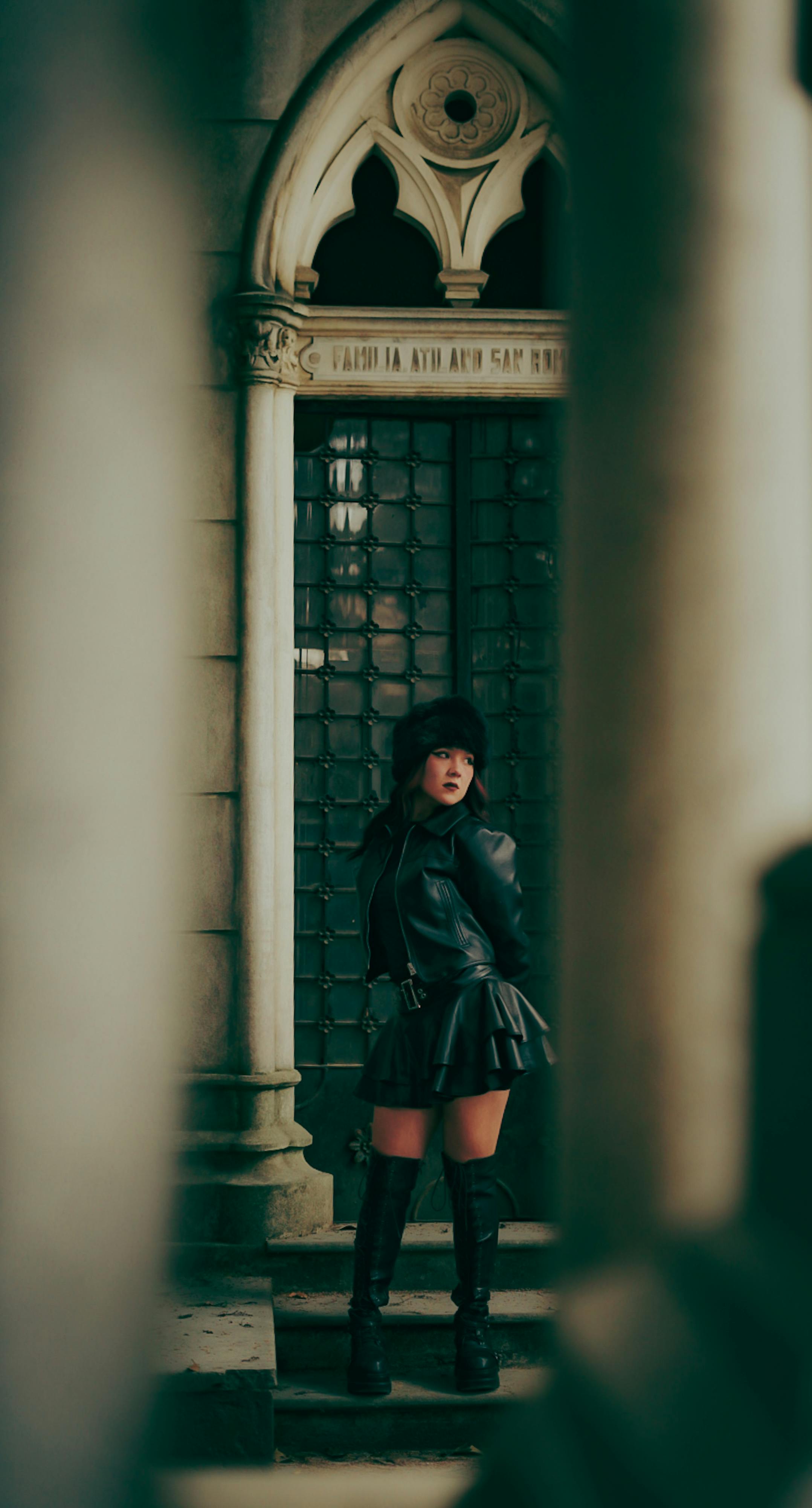 Gratis Mujer vestida de cuero negro posando junto a una arquitectura gótica ornamentada con un ambiente misterioso. Foto de stock