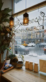 Warm interior of a Brooklyn coffee shop with a snowy street view, creating a cozy urban atmosphere.