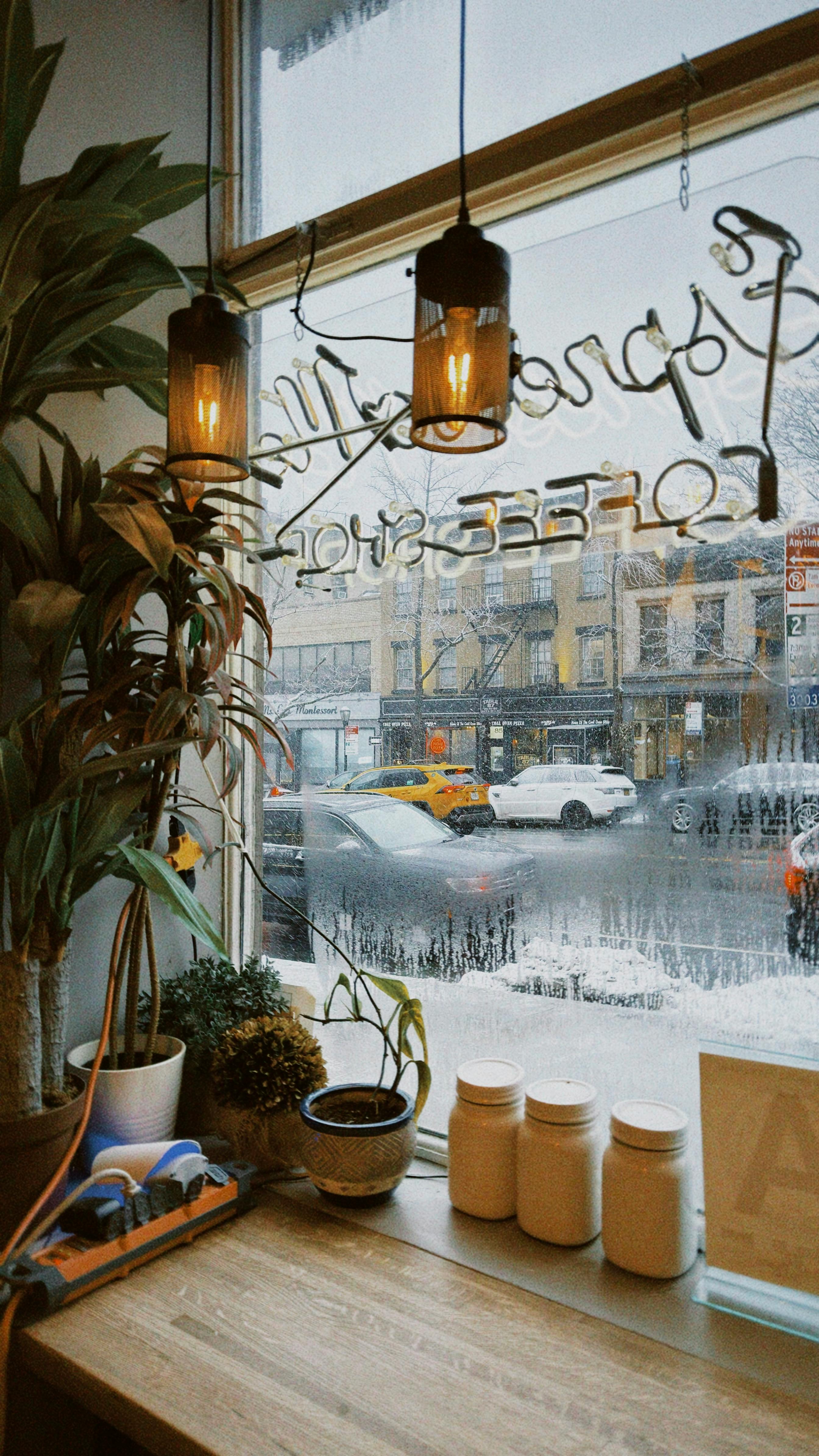 bezplatná Teplý interiér brooklynské kavárny s výhledem na zasněžené ulice, který vytváří útulnou městskou atmosféru. Základová fotografie