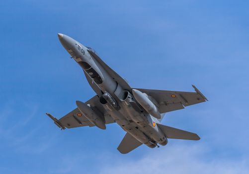 Spanish Air Force F-18 fighter jet soaring through clear blue sky over Albacete, Spain.