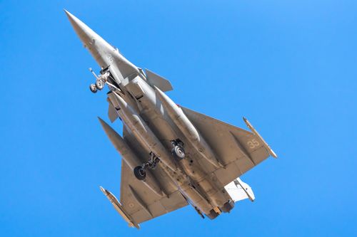 Free A Rafale fighter jet flying against a clear blue sky, viewed from below. Stock Photo