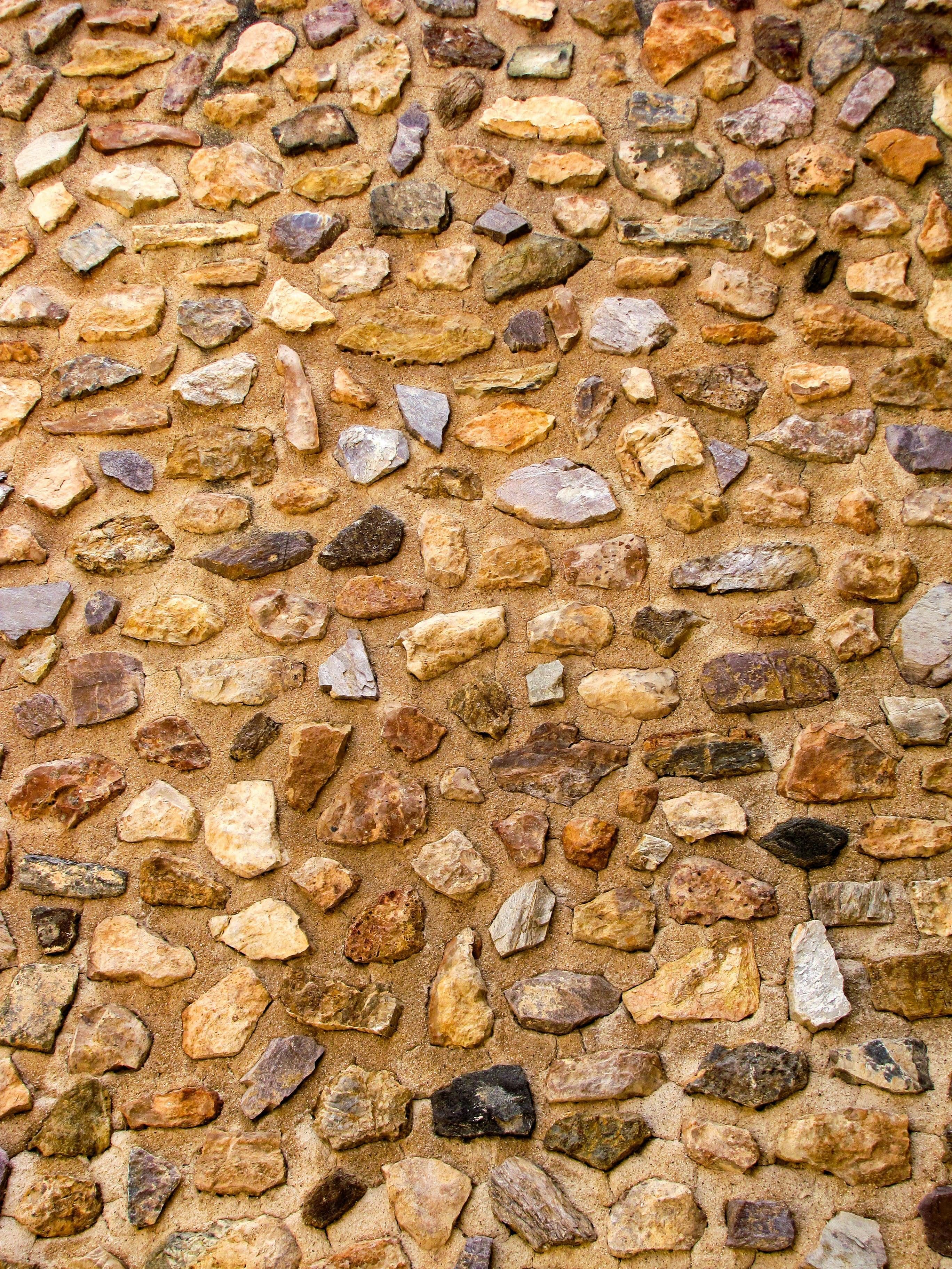 Free Close-up of a rustic stone wall texture showcasing diverse rock patterns in Cartagena, Spain. Stock Photo