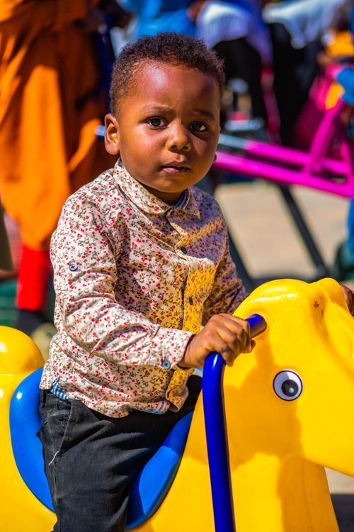 Free A young child on a colorful playground ride in Zaria City, Nigeria, enjoying a sunny day. Stock Photo