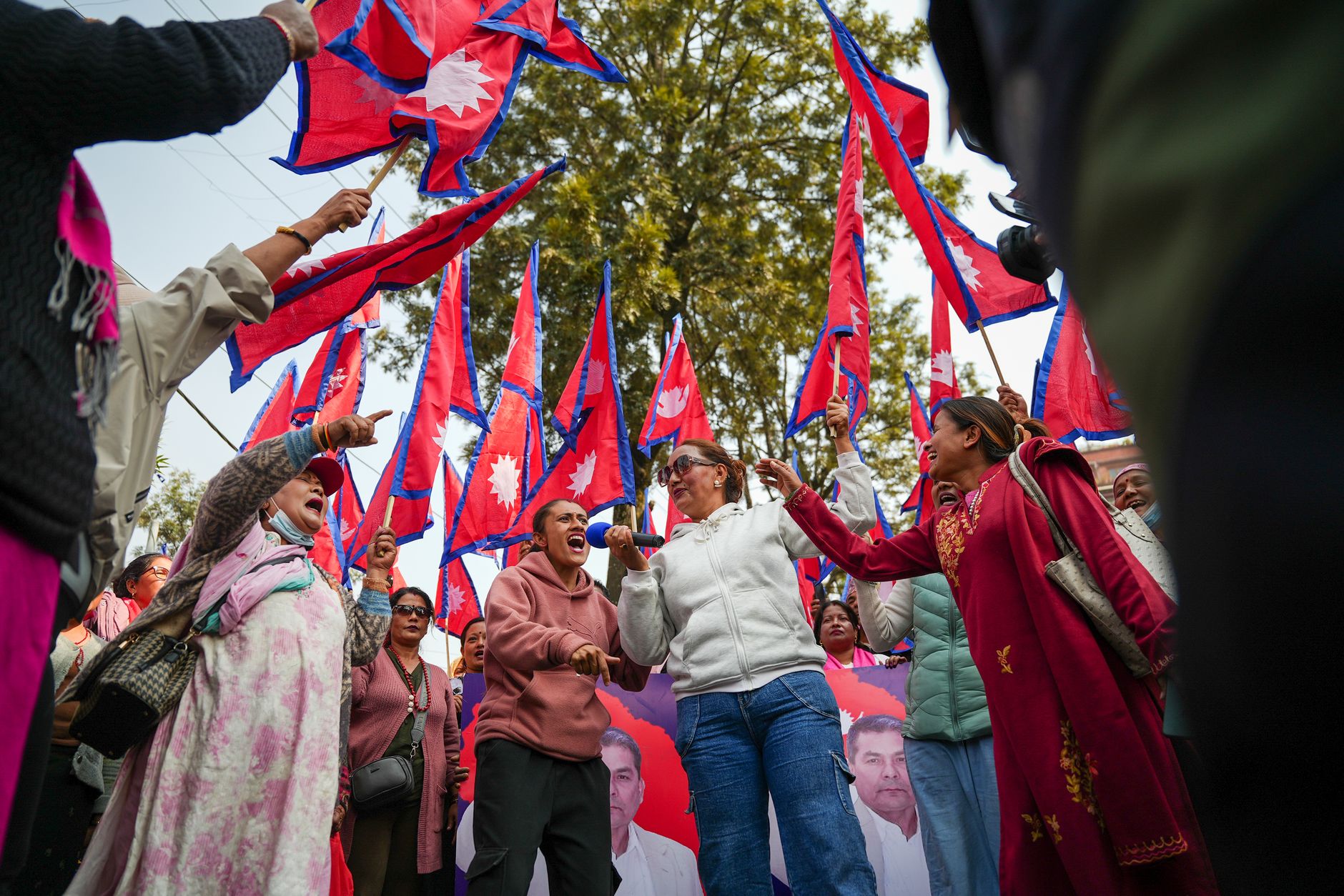 Group of Nepalese people protesting with national flags held high in outdoor rally.