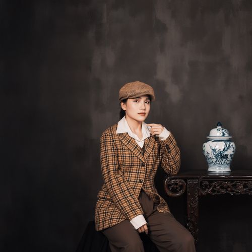 Free A classic portrait of a person sitting beside an ornate porcelain vase on a wooden table. Stock Photo