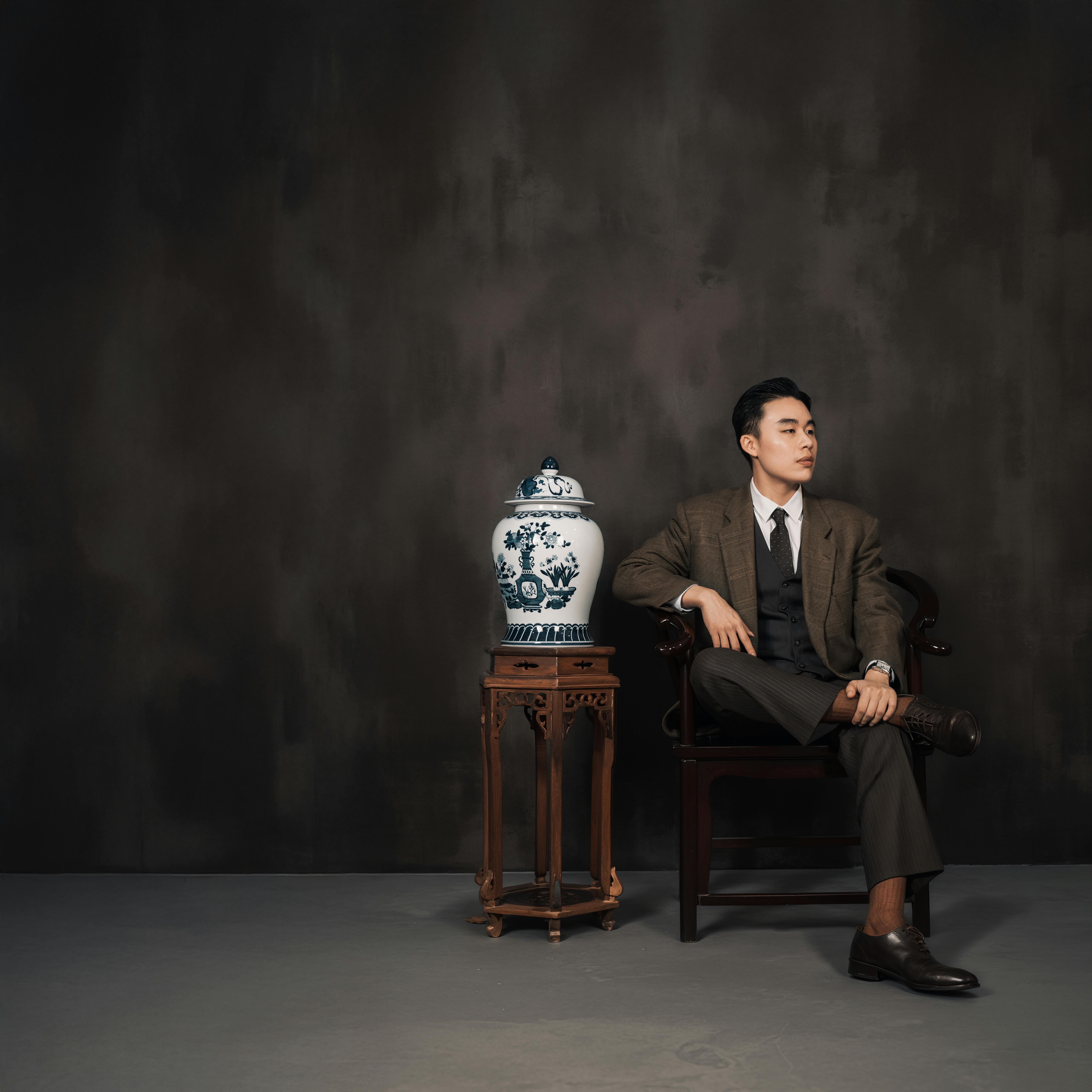 Portrait of a man in a classic suit next to a neoclassical ceramic vase.