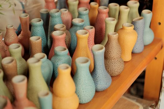A collection of vibrant ceramic vases displayed on shelves in Hội An, Vietnam, showcasing artistic craft.