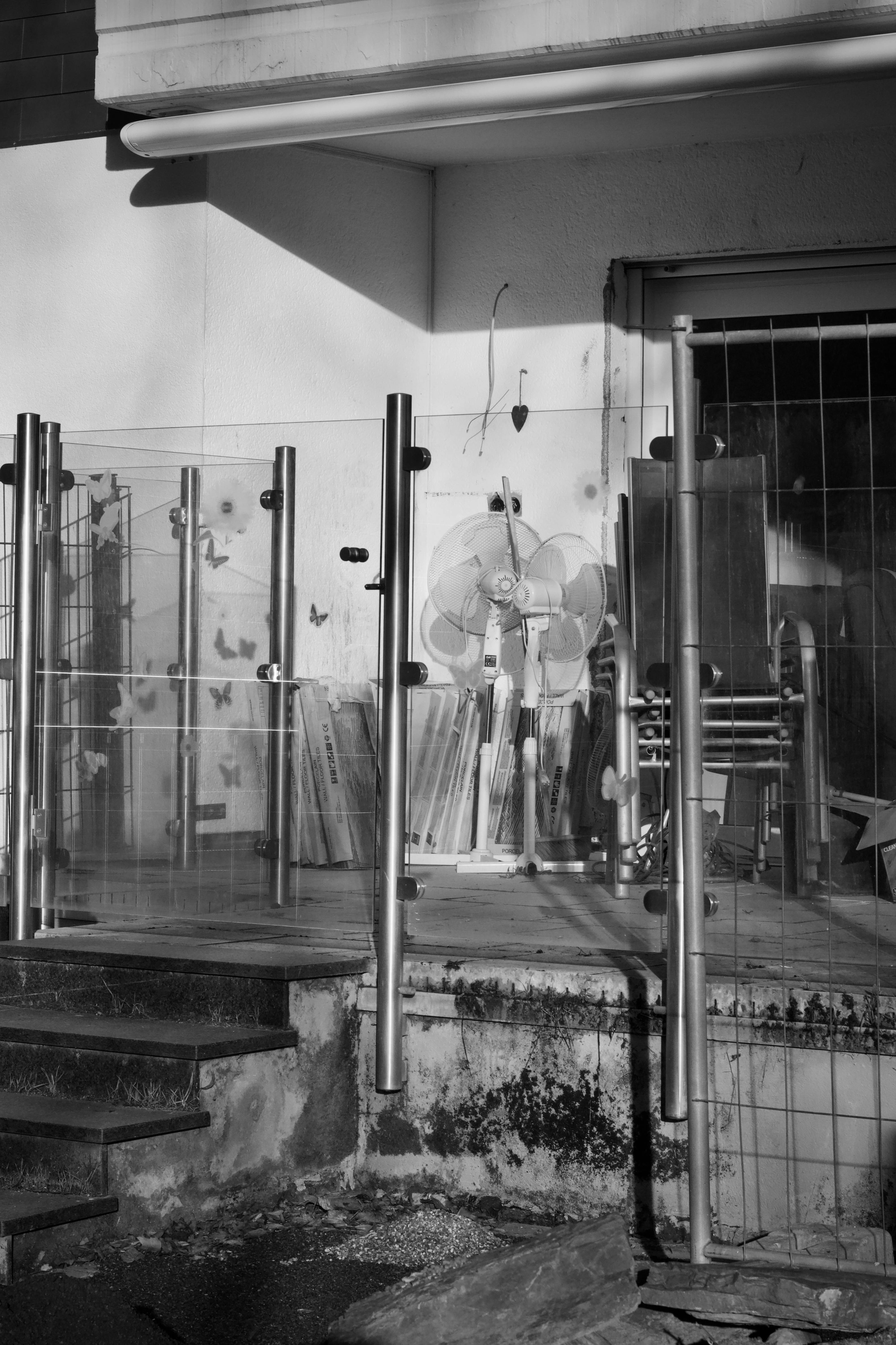 無料 ガラスのフェンス、ファン、影がドラマチックな効果を生み出す工業地帯のモノクロ画像。 写真素材