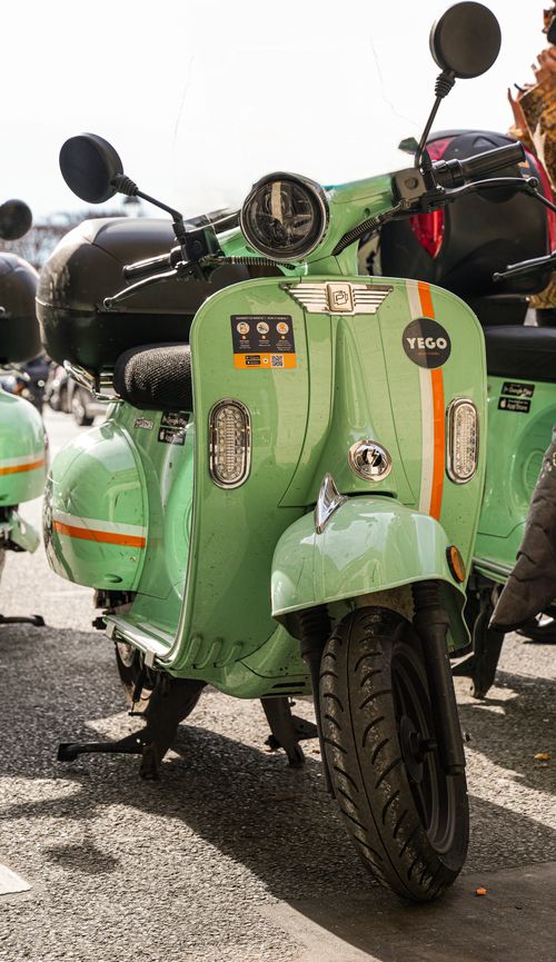 Free Stylish green scooter with emblem, parked on an urban street, capturing retro vibes. Stock Photo
