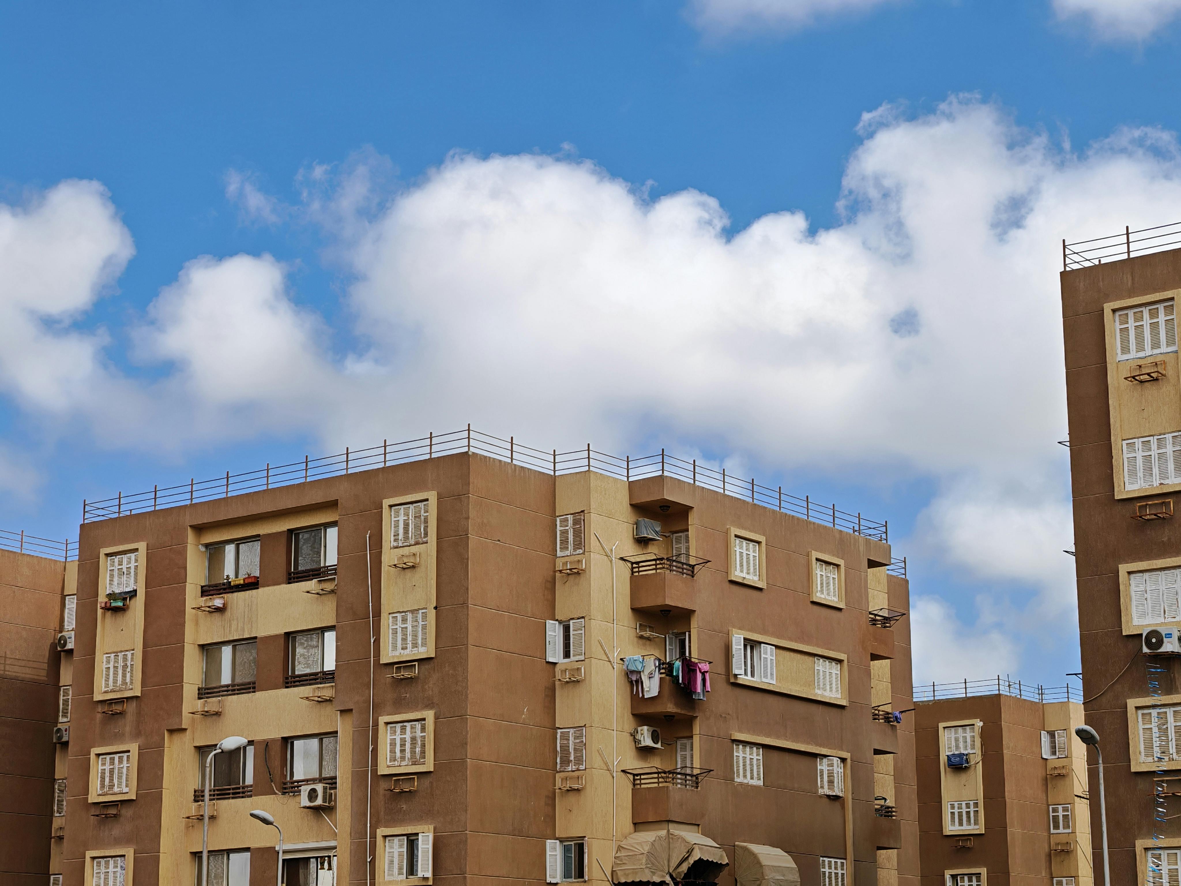 Gratis Udsigt over en lejlighedsbygning under en lys blå himmel med luftige skyer. Lagerfoto