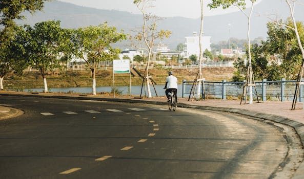 A cyclist rides along a scenic road in Kon Tum, Vietnam. Serene summer morning.