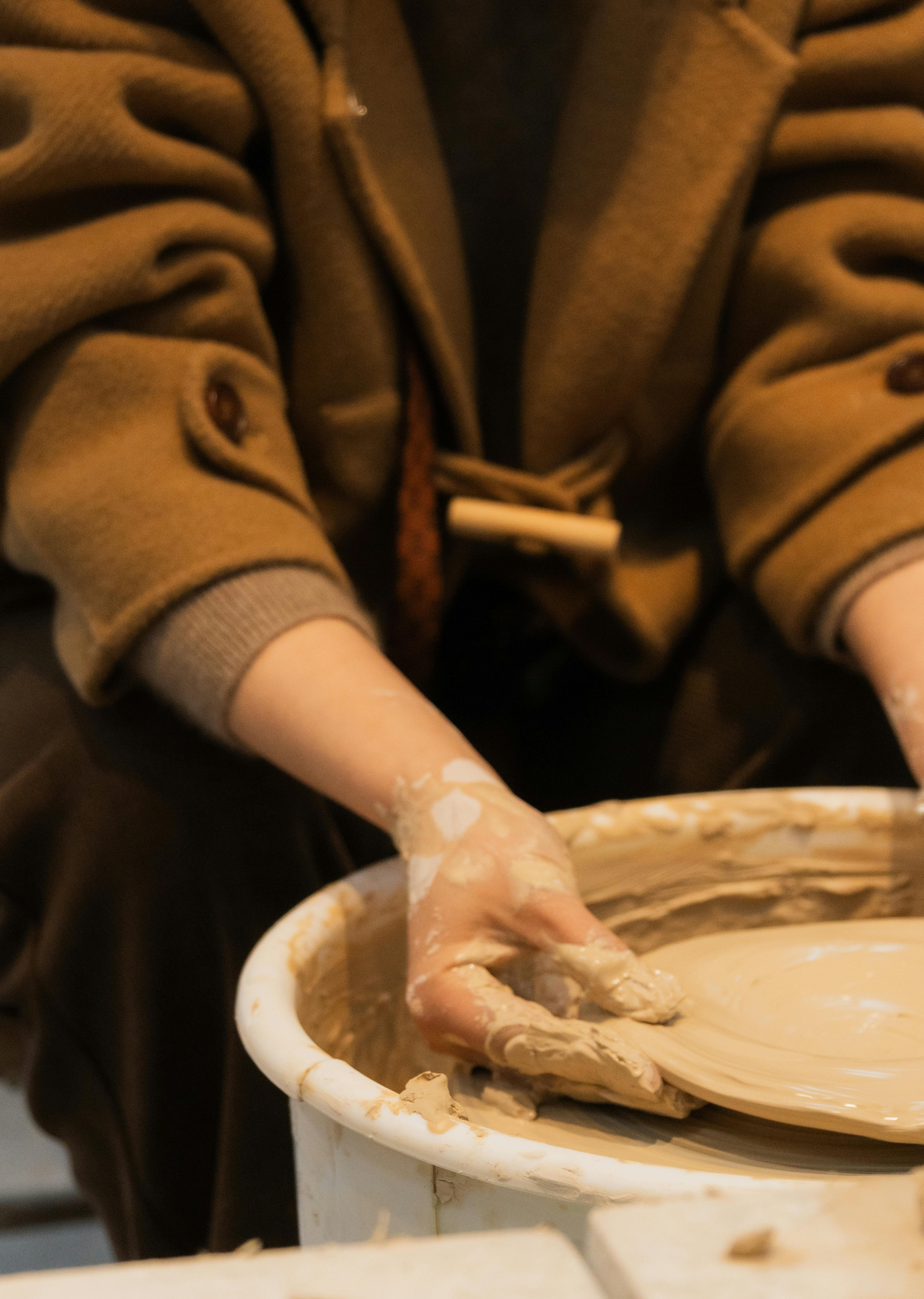 Gratis En person former dygtigt ler på en drejeskive og demonstrerer dermed kunstnerisk håndværk. Lagerfoto