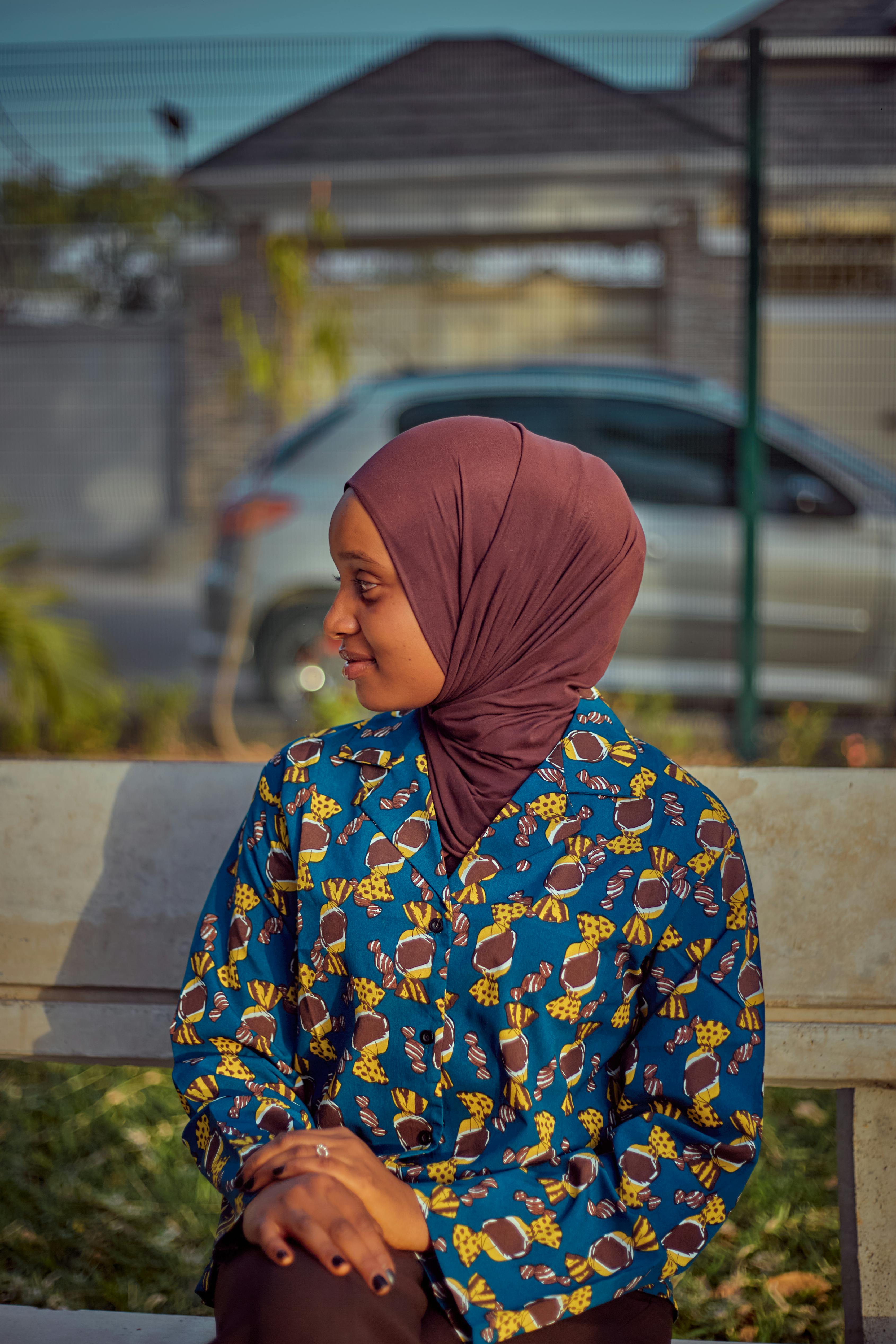 Gratis Portrett av en ung kvinne i hijab som sitter utendørs og ser til siden. Arkivbilde