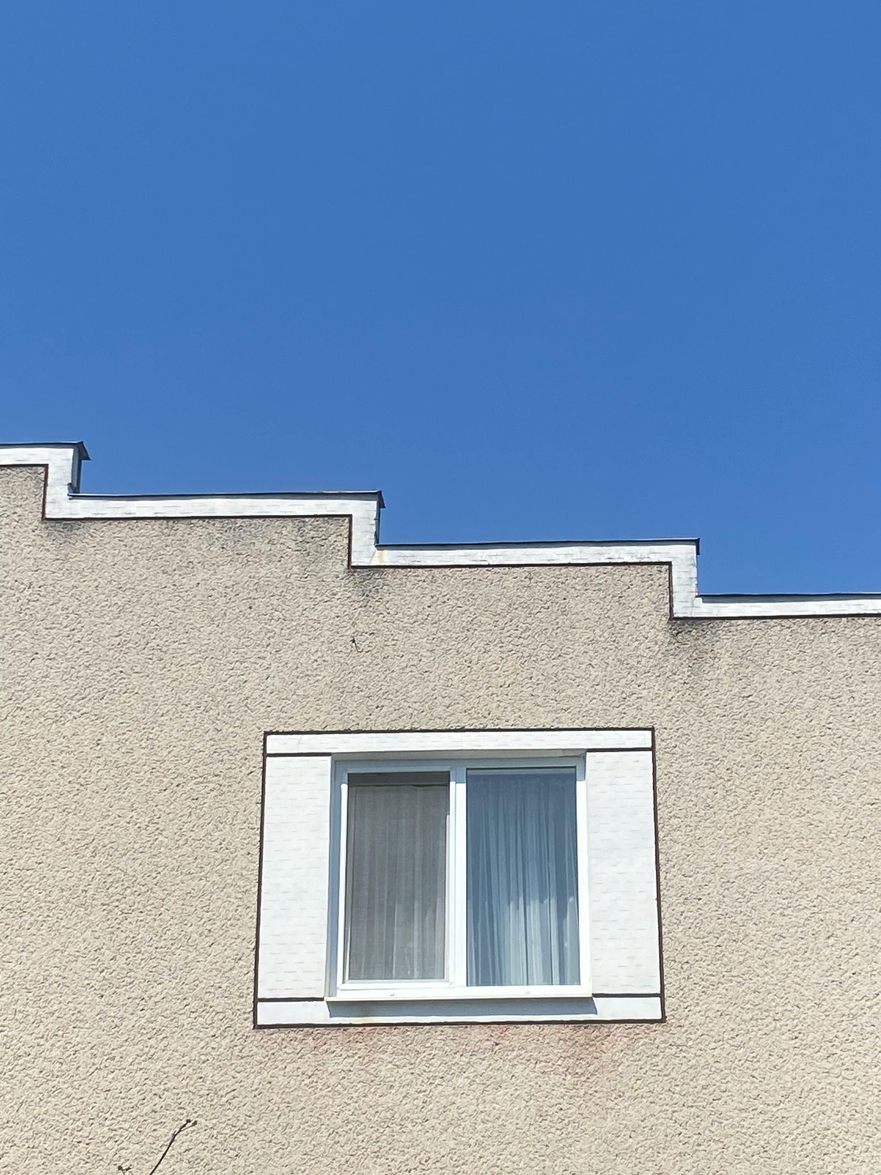 Gratuit Un exterior minimalist de clădire bej, cu un acoperiș distinct în zig-zag pe un cer albastru senin. Fotografie de stoc