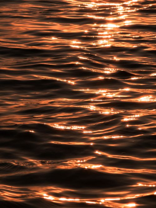 Free Close-up of golden sunlight reflecting on the waves at Karachi's shoreline. Stock Photo