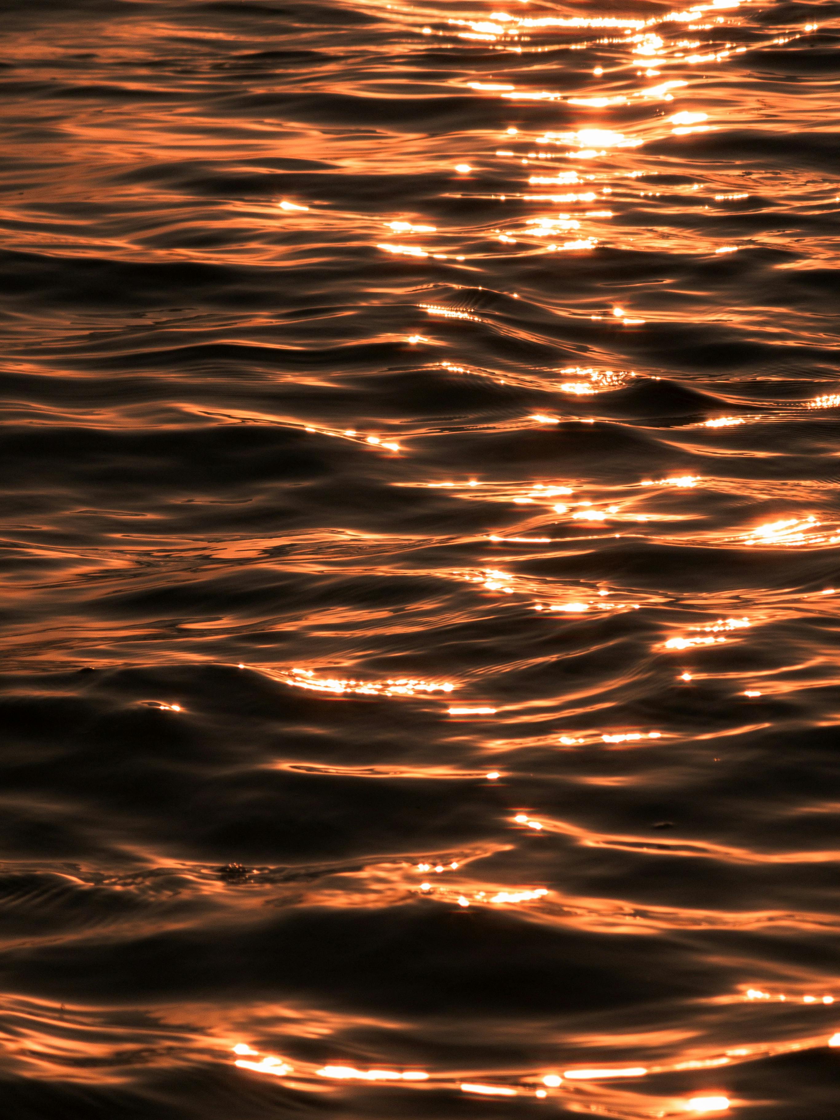 Gratis Tampilan jarak dekat cahaya matahari keemasan yang terpantul di ombak di garis pantai Karachi. Foto Stok