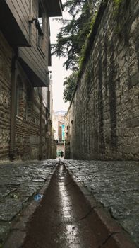 A narrow stone alleyway with rustic buildings, creating an aged and atmospheric scene.