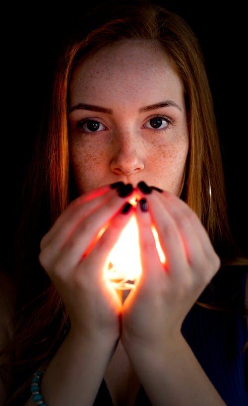 Woman Holding Lighted Candle in Front of Her Face