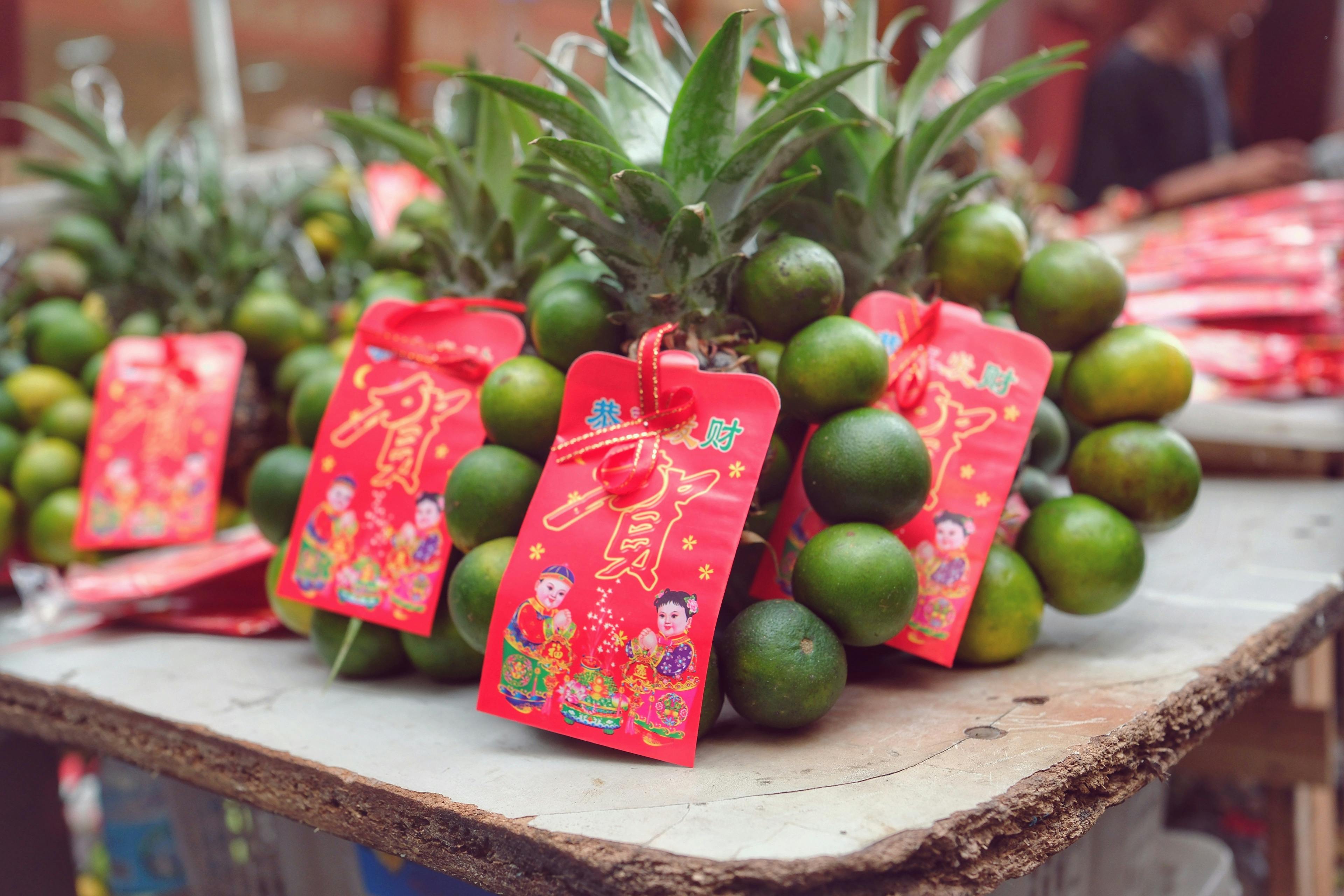 Gratis Farverig ananas- og calamansi-udstilling med festlige røde etiketter i asiatisk tema, perfekt til fester. Lagerfoto