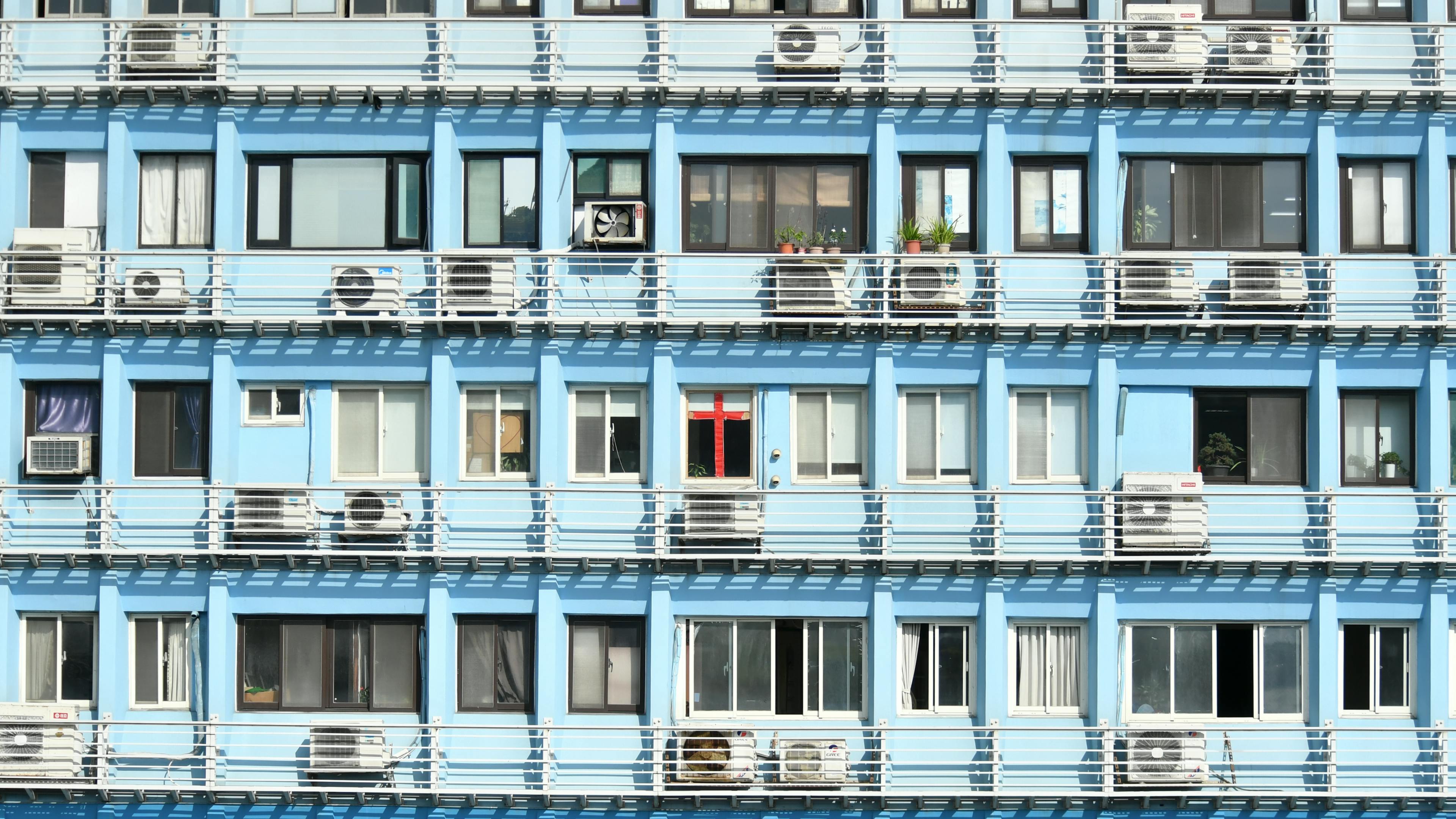 бесплатная Красочный синий фасад многоквартирного дома с окнами и кондиционерами. Стоковое фото