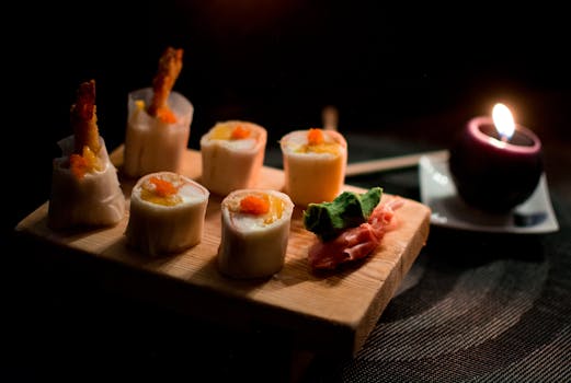 Elegant sushi presentation with sushi rolls, garnishes, and candlelight.