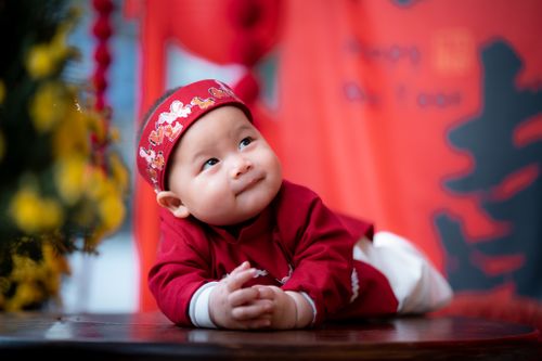 Free Adorable baby in vibrant traditional Vietnamese attire with a festive backdrop. Stock Photo