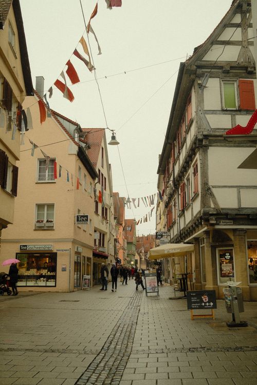 Free Atmospheric view of a quaint street in Ulm, Germany, with traditional architecture and festive flags. Stock Photo