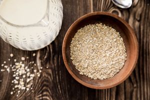 Wooden bowl of rolled oats beside a milk jug — photo by Victoria Bowers on Pexels