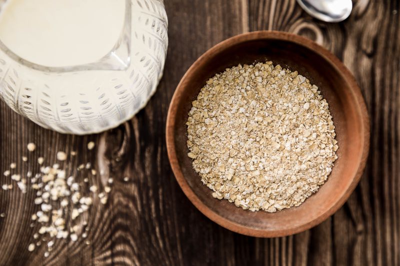 Jug of oat milk beside a bowl of oats on a rustic table — photo by Victoria Bowers on Pexels