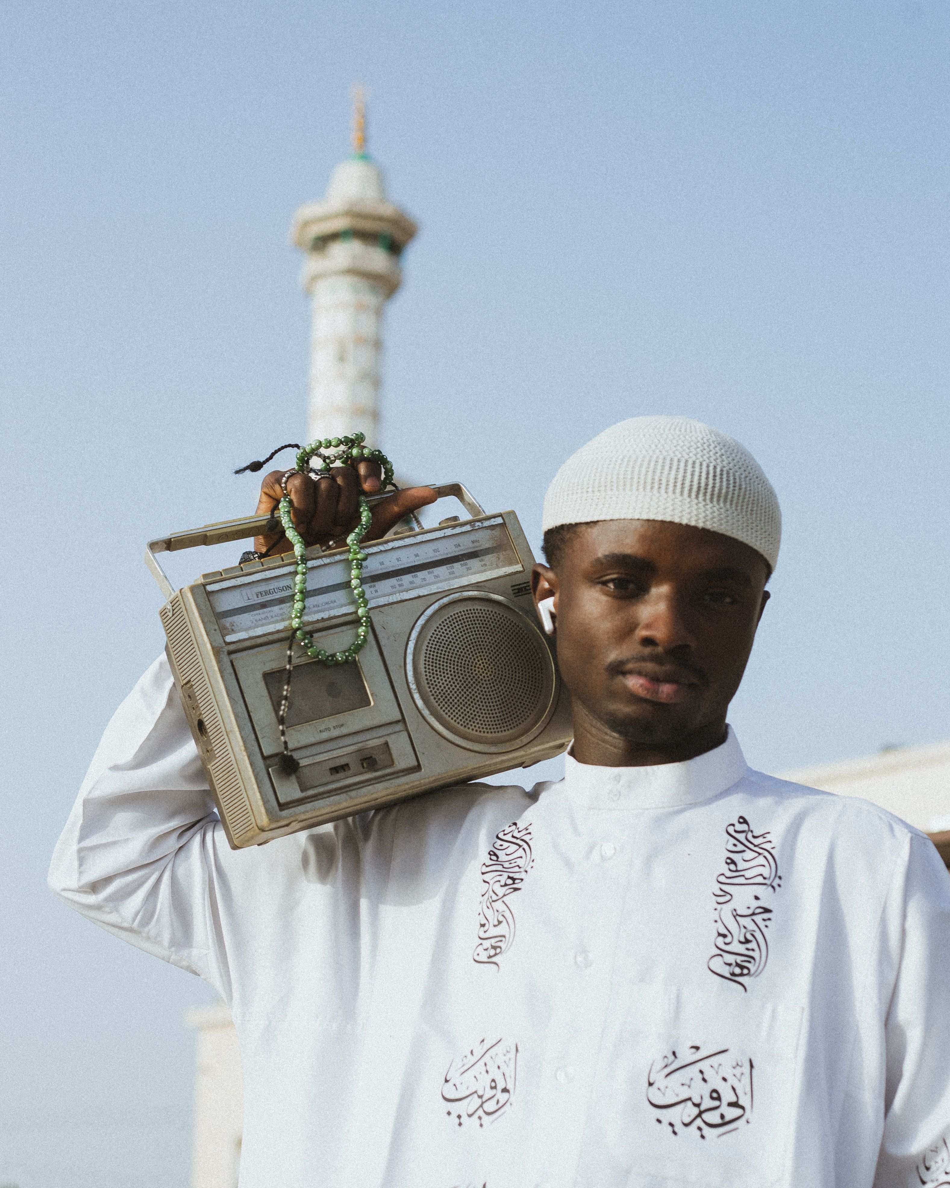 Man holding a vintage radio with mosque in the background, Kano, Nigeria.