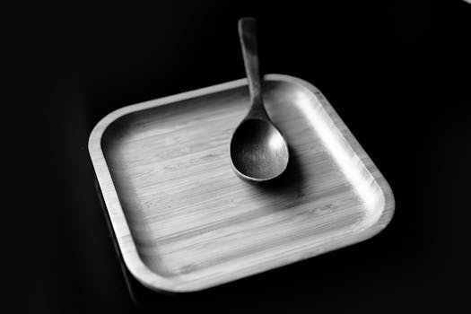 Elegant black and white photo of a bamboo plate and spoon, highlighting minimalist design.