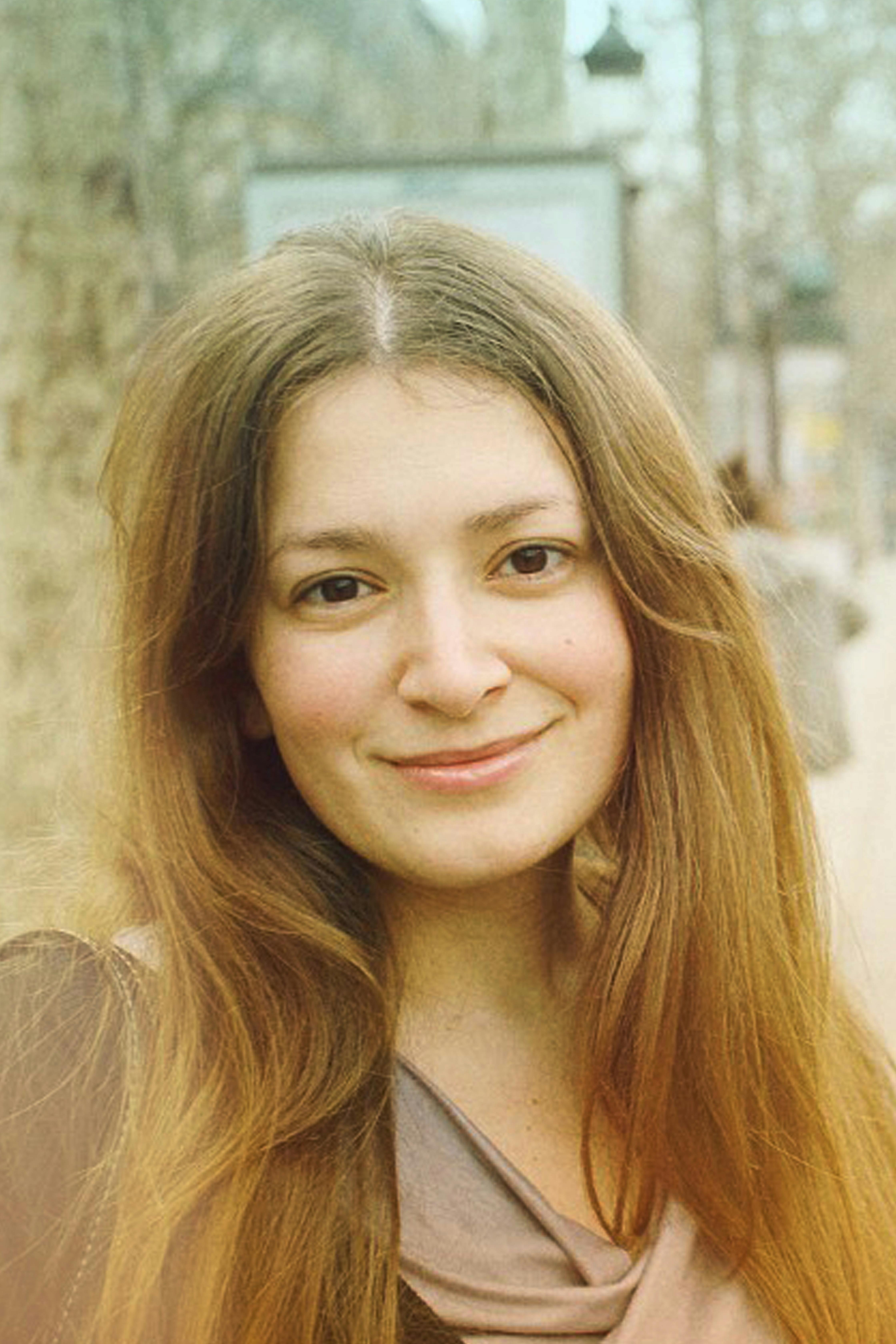 A serene vintage-style portrait of a smiling woman outdoors with a soft, warm tone.