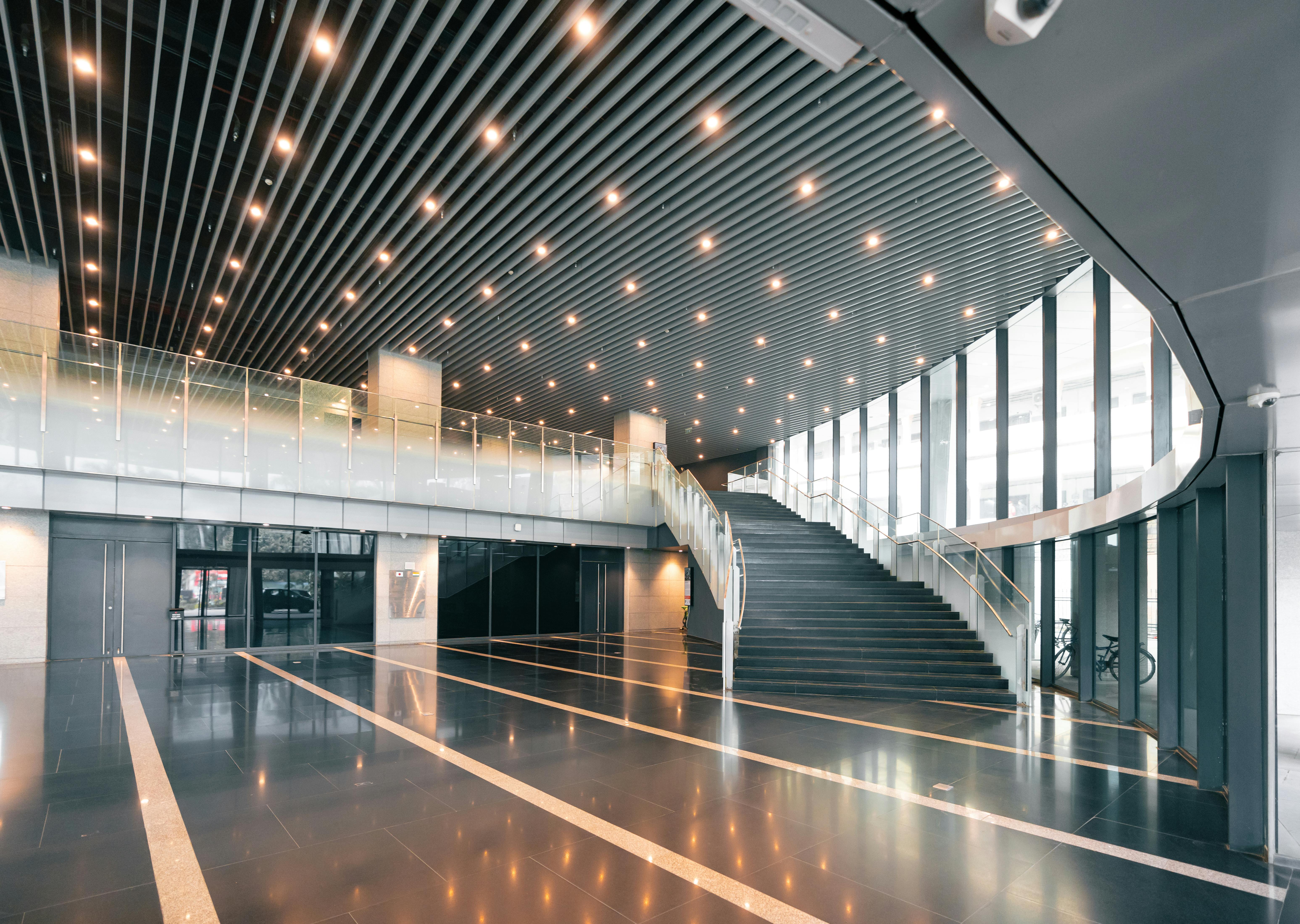 бесплатная Просторный современный офисный интерьер с элегантной винтовой лестницей и потолочным освещением. Стоковое фото