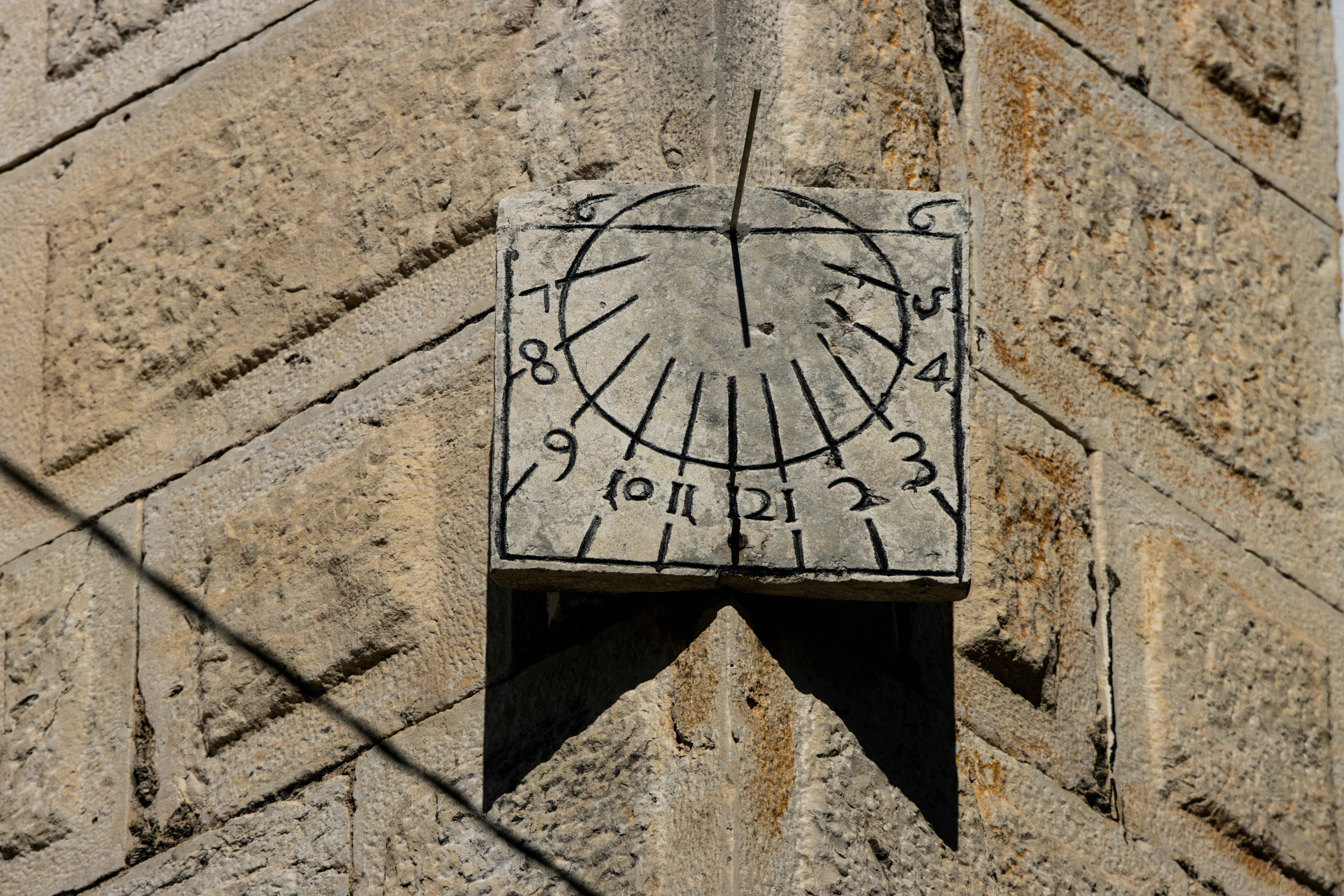 無料 古い石壁に影を落とす伝統的な石造りの日時計のクローズアップ。 写真素材