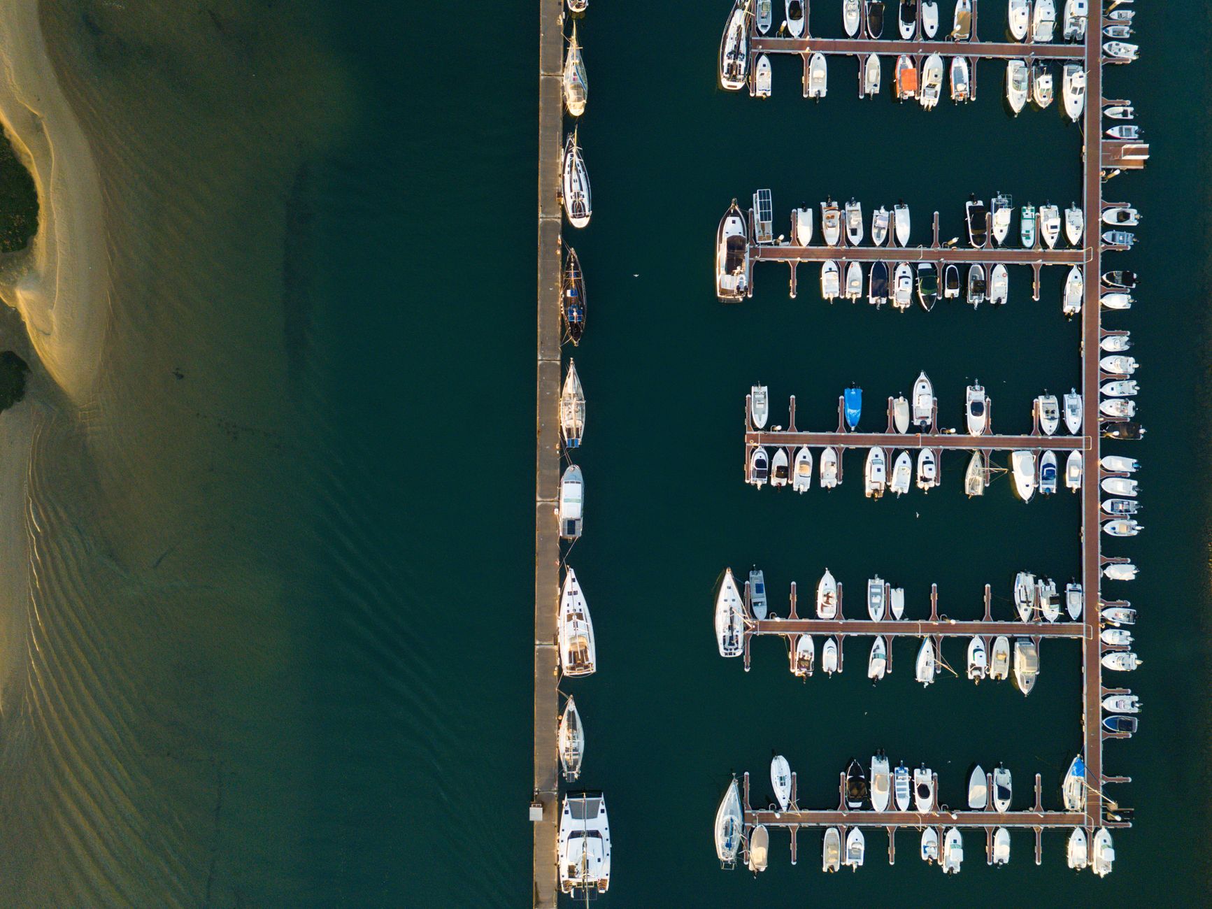Top-down view of Olhão marina with docked boats and sandy shoreline.