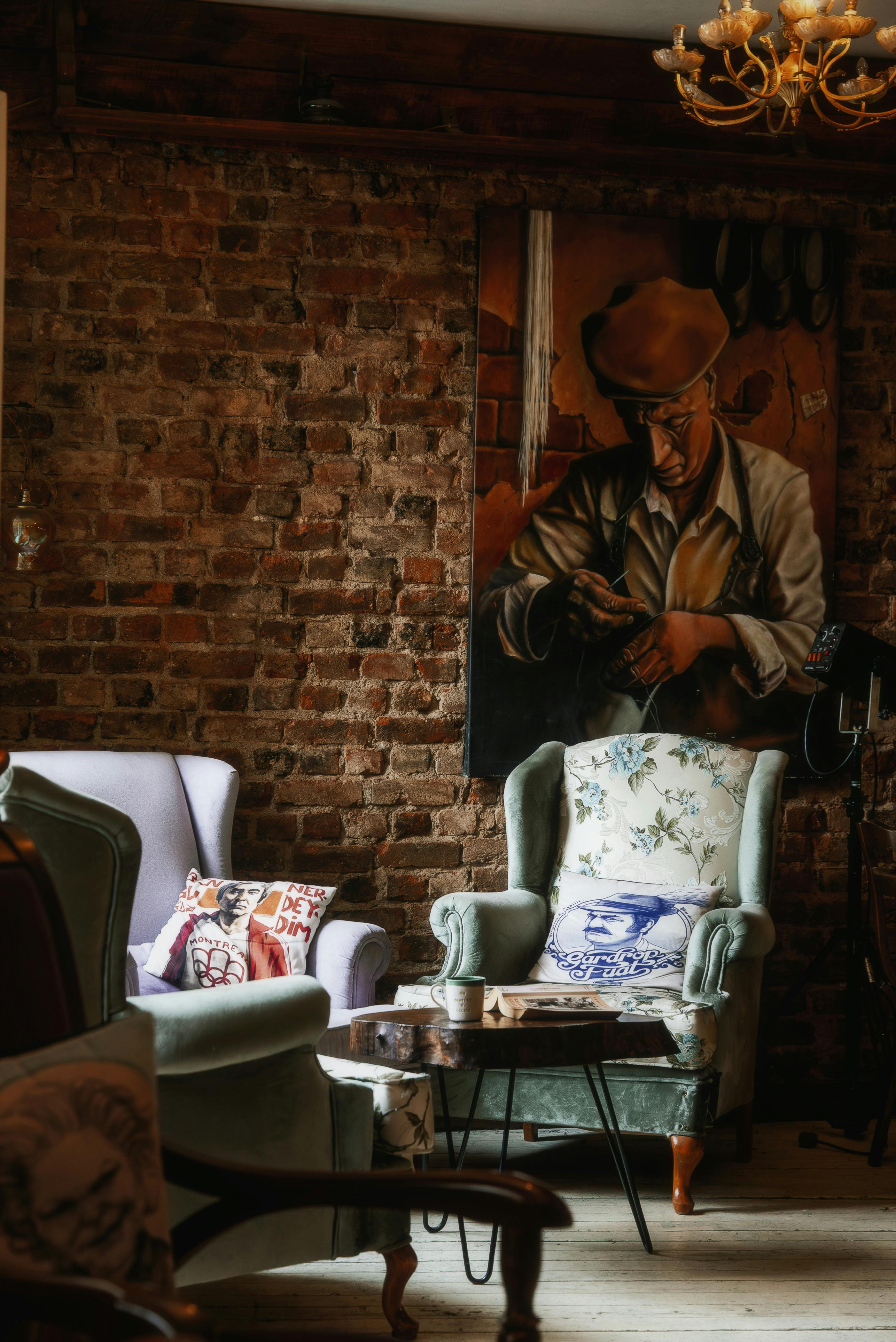 бесплатная Уютная гостиная в винтажном стиле с комфортными креслами, кирпичной стеной и произведениями искусства. Стоковое фото