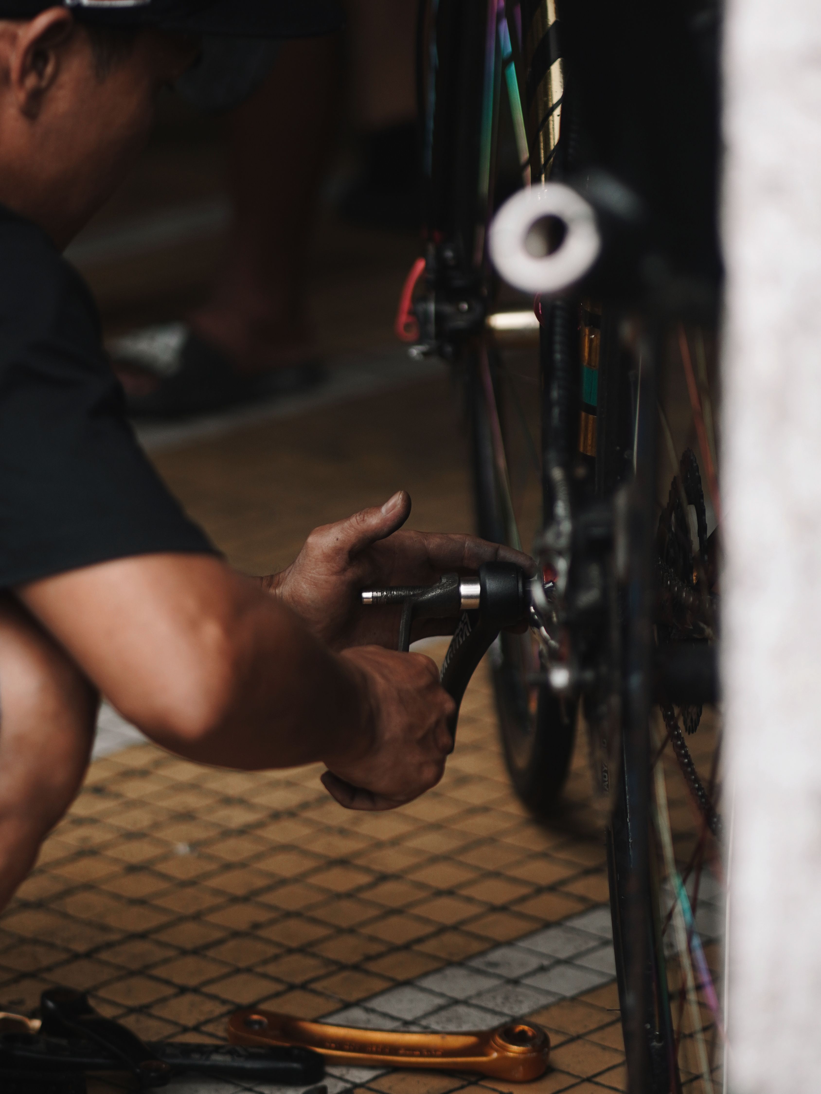 A person fixes a bicycle wheel indoors, focusing on maintenance tasks.