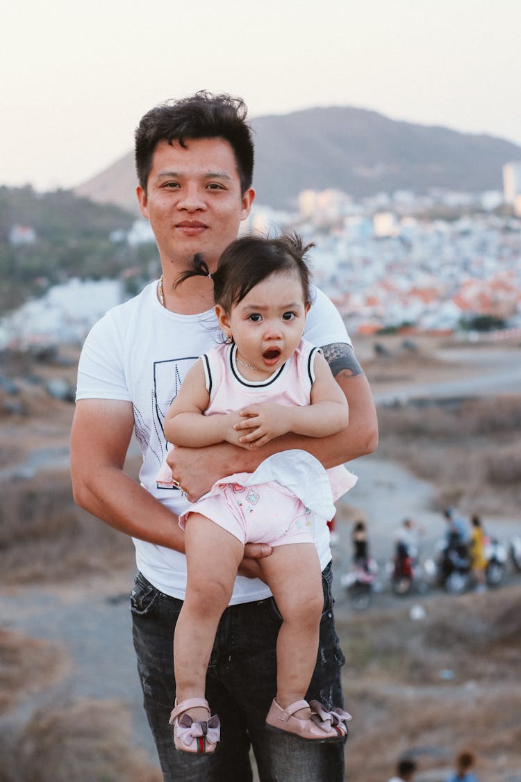 Man In White Crew Neck T-shirt Carrying A Baby Girl