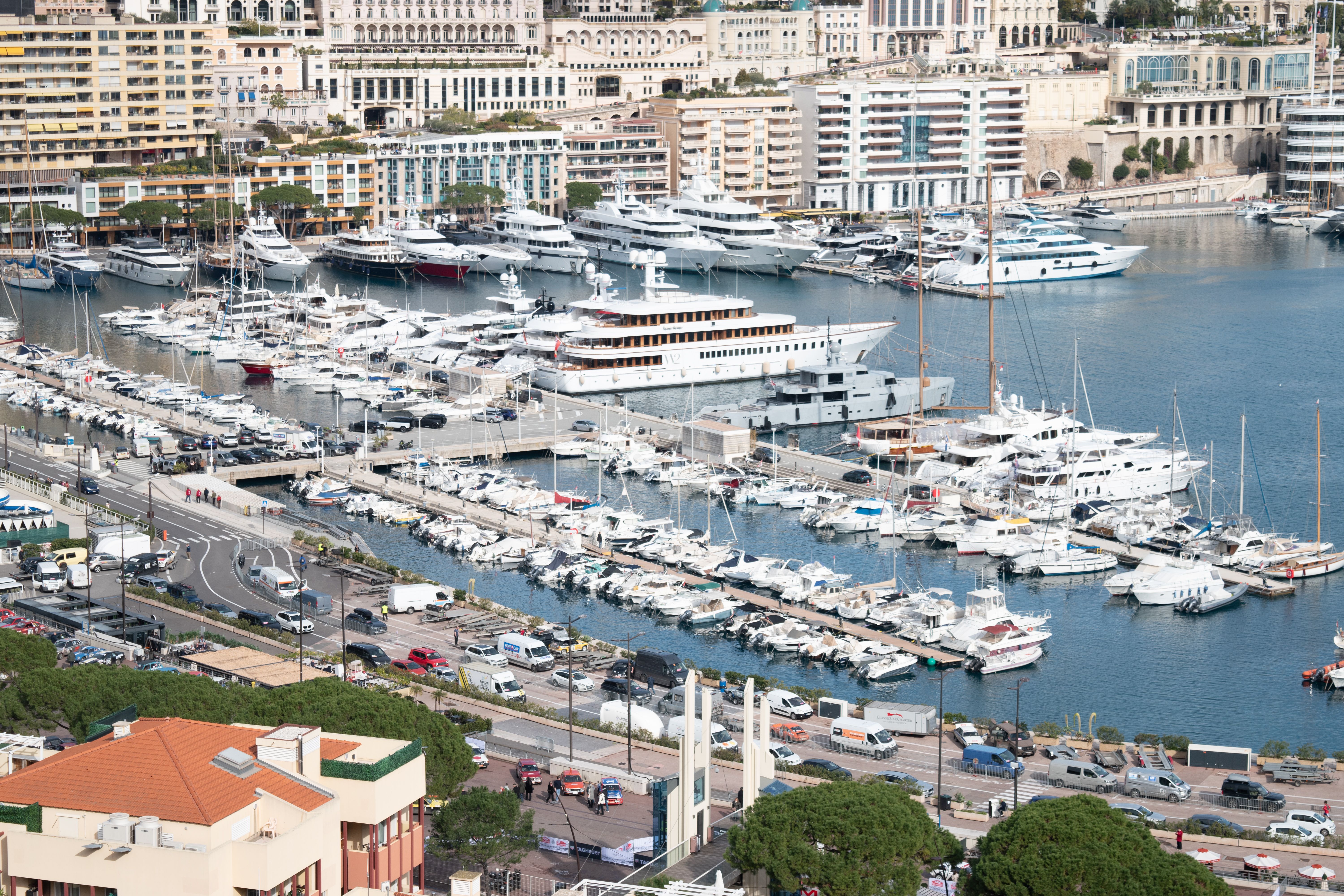 Aerial view of luxury yachts in Monte Carlo harbor, showcasing waterfront architecture and bustling marina.
